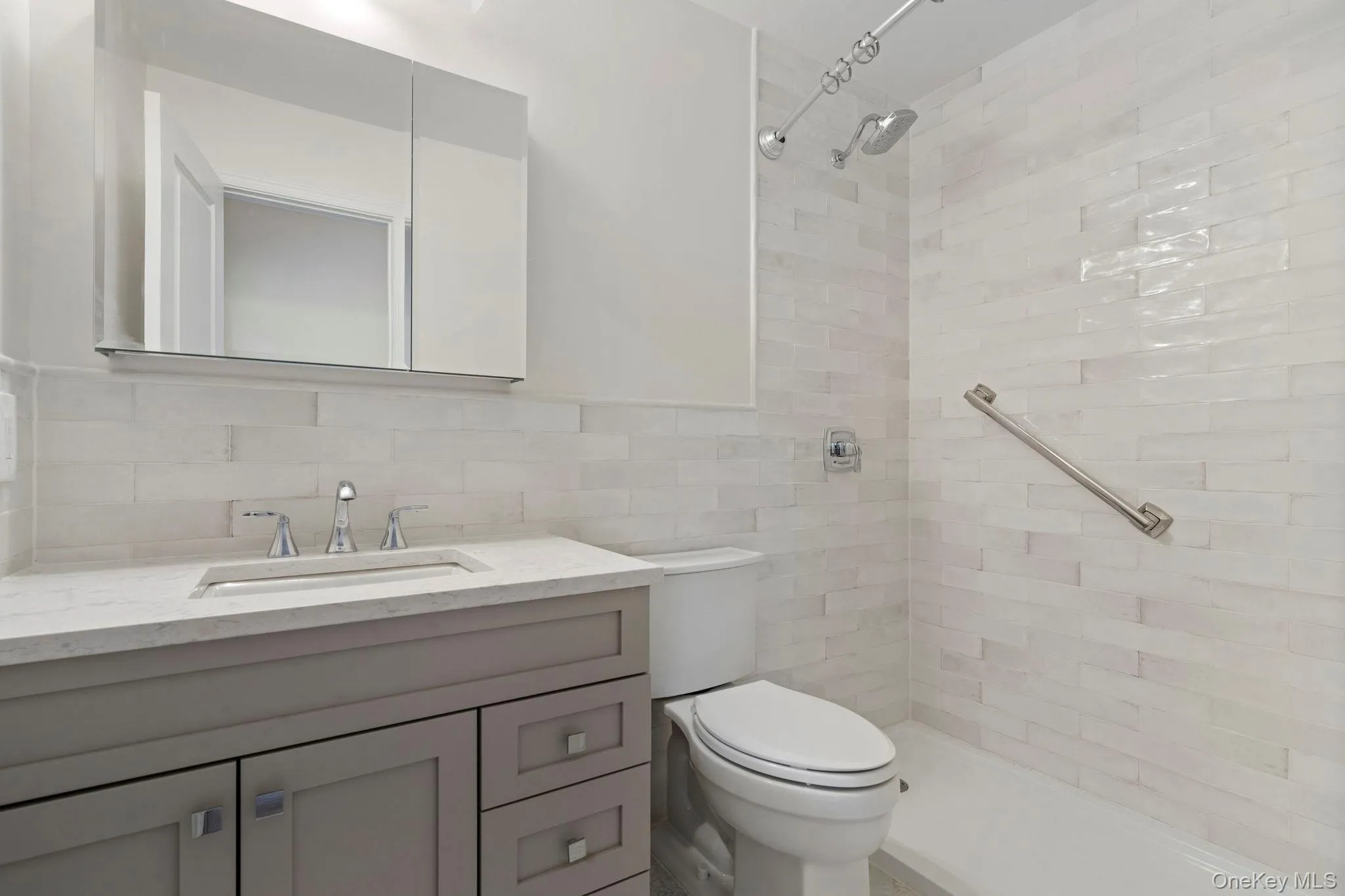 Bathroom with vanity, a tile shower, and tile walls Bathroom with vanity, a tile shower, and tile walls