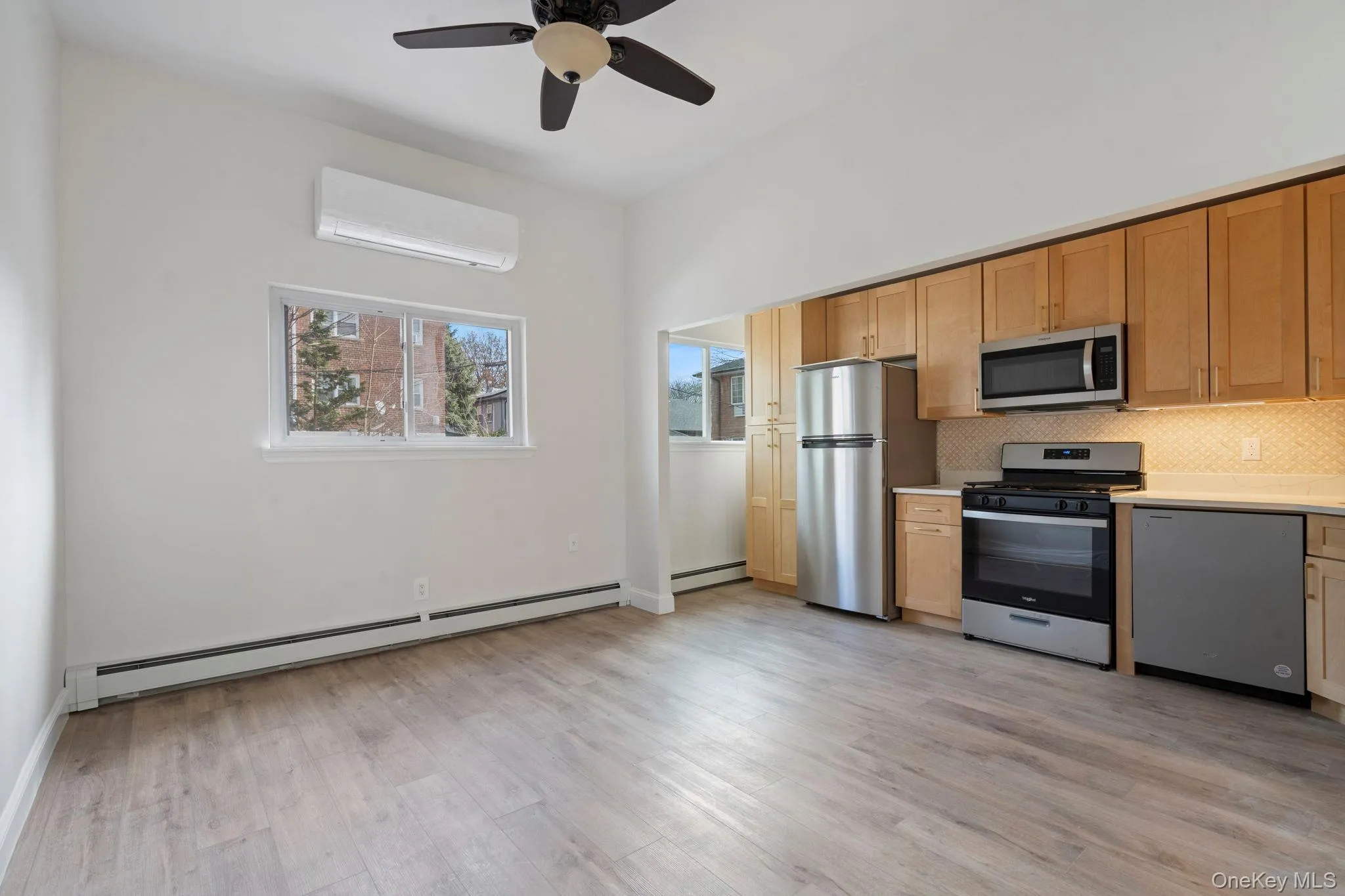 Kitchen featuring appliances with stainless steel finishes, tasteful backsplash, a baseboard radiator, a wall mounted AC, and ceiling fan Kitchen featuring appliances with stainless steel finishes, tasteful backsplash, a baseboard radiator, a wall mounted AC, and ceiling fan