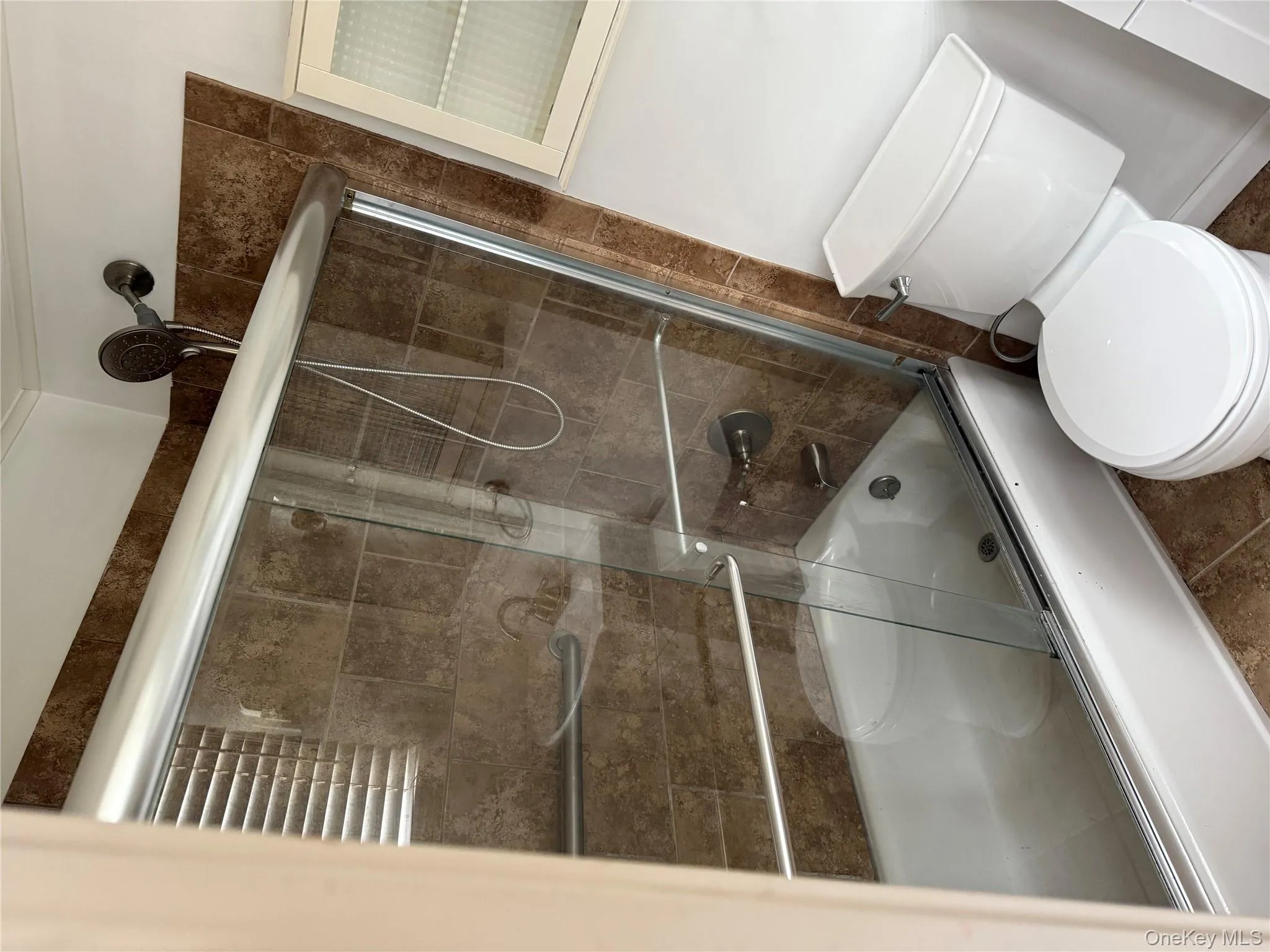 Bathroom with combined bath / shower with glass door and toilet Bathroom with combined bath / shower with glass door and toilet