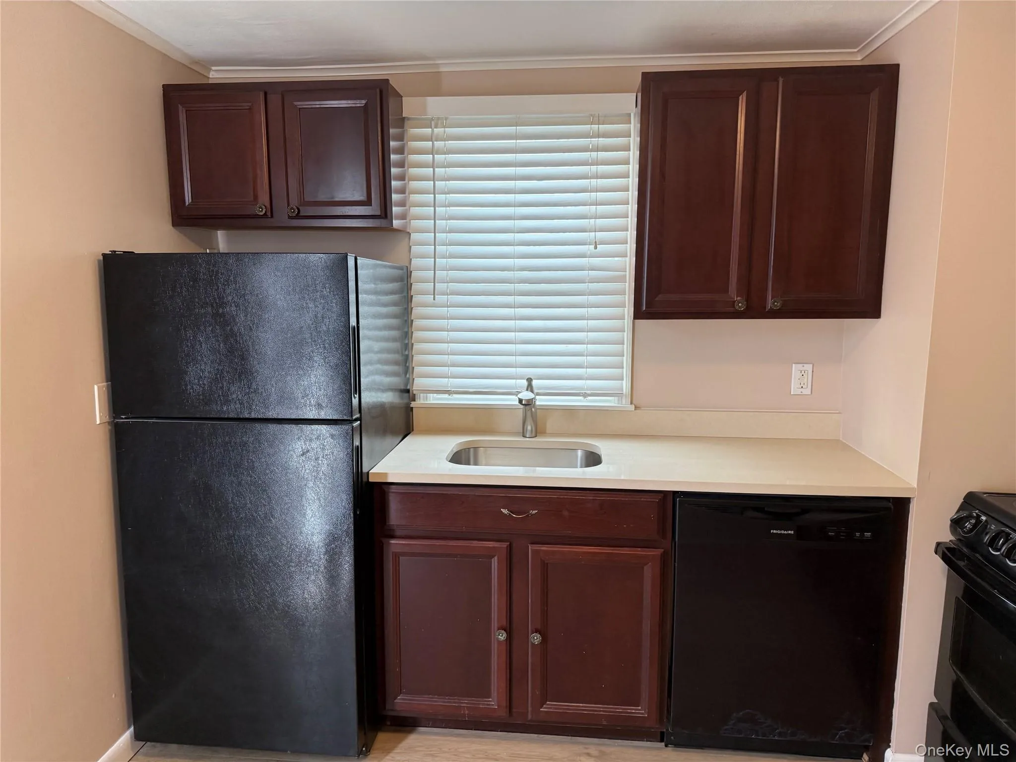 Kitchen with black appliances, ornamental molding, and dark brown cabinets Kitchen with black appliances, ornamental molding, and dark brown cabinets