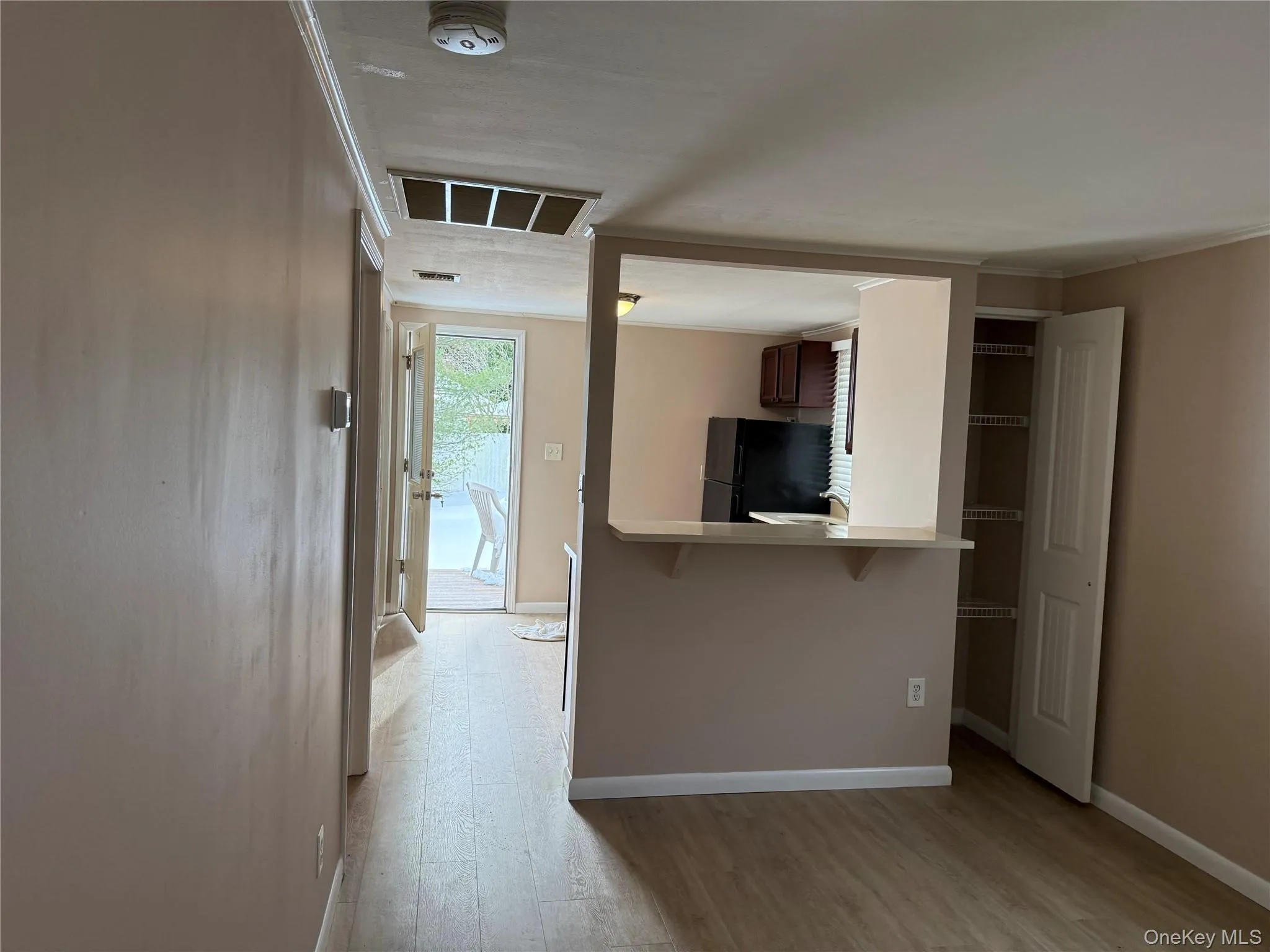 Kitchen featuring a kitchen bar, light wood-style flooring, light countertops, freestanding refrigerator, and crown molding Kitchen featuring a kitchen bar, light wood-style flooring, light countertops, freestanding refrigerator, and crown molding