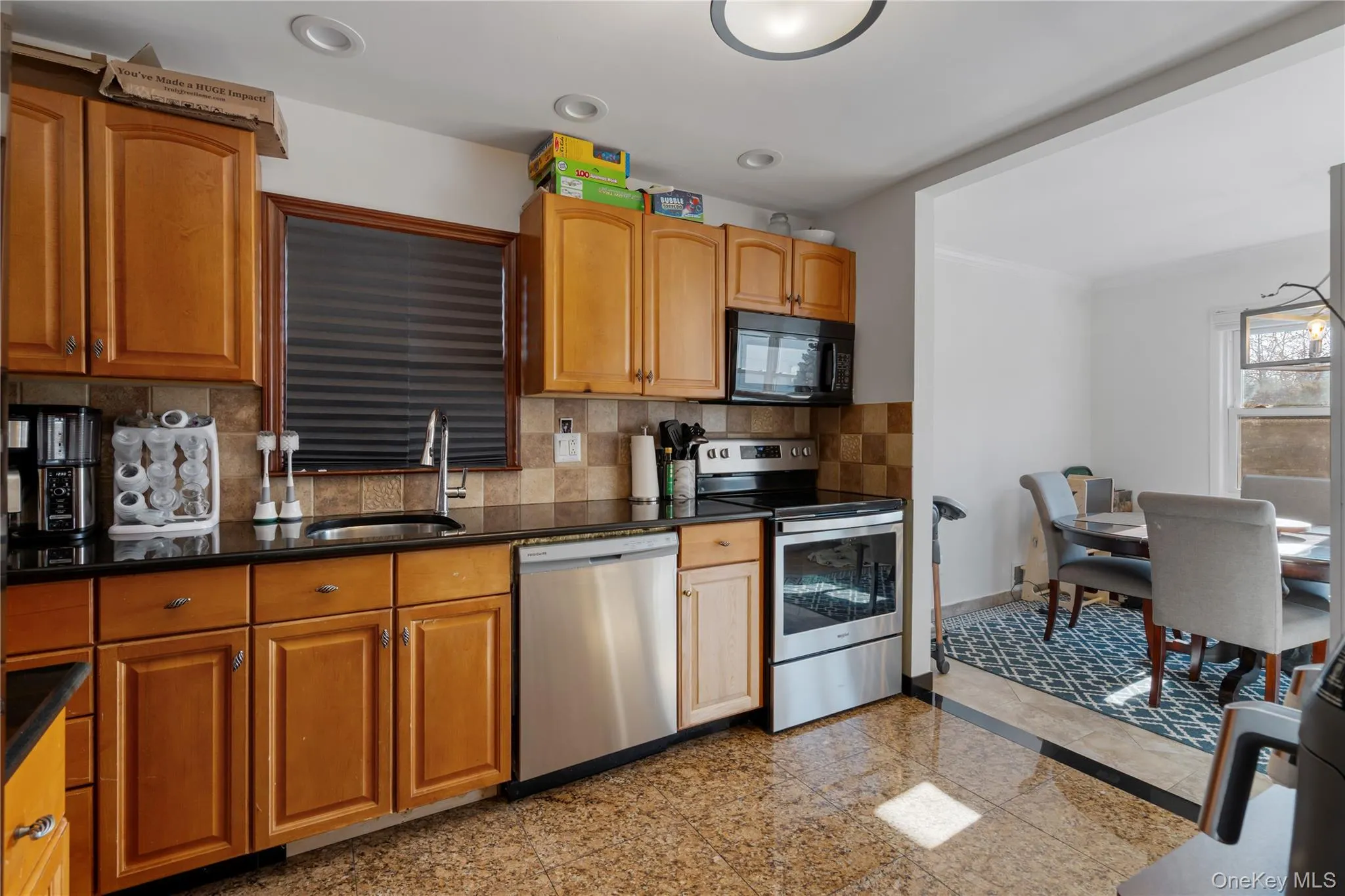Kitchen with appliances with stainless steel finishes, granite tiled floors, tasteful backsplash, brown cabinets, and crown molding Kitchen with appliances with stainless steel finishes, granite tiled floors, tasteful backsplash, brown cabinets, and crown molding
