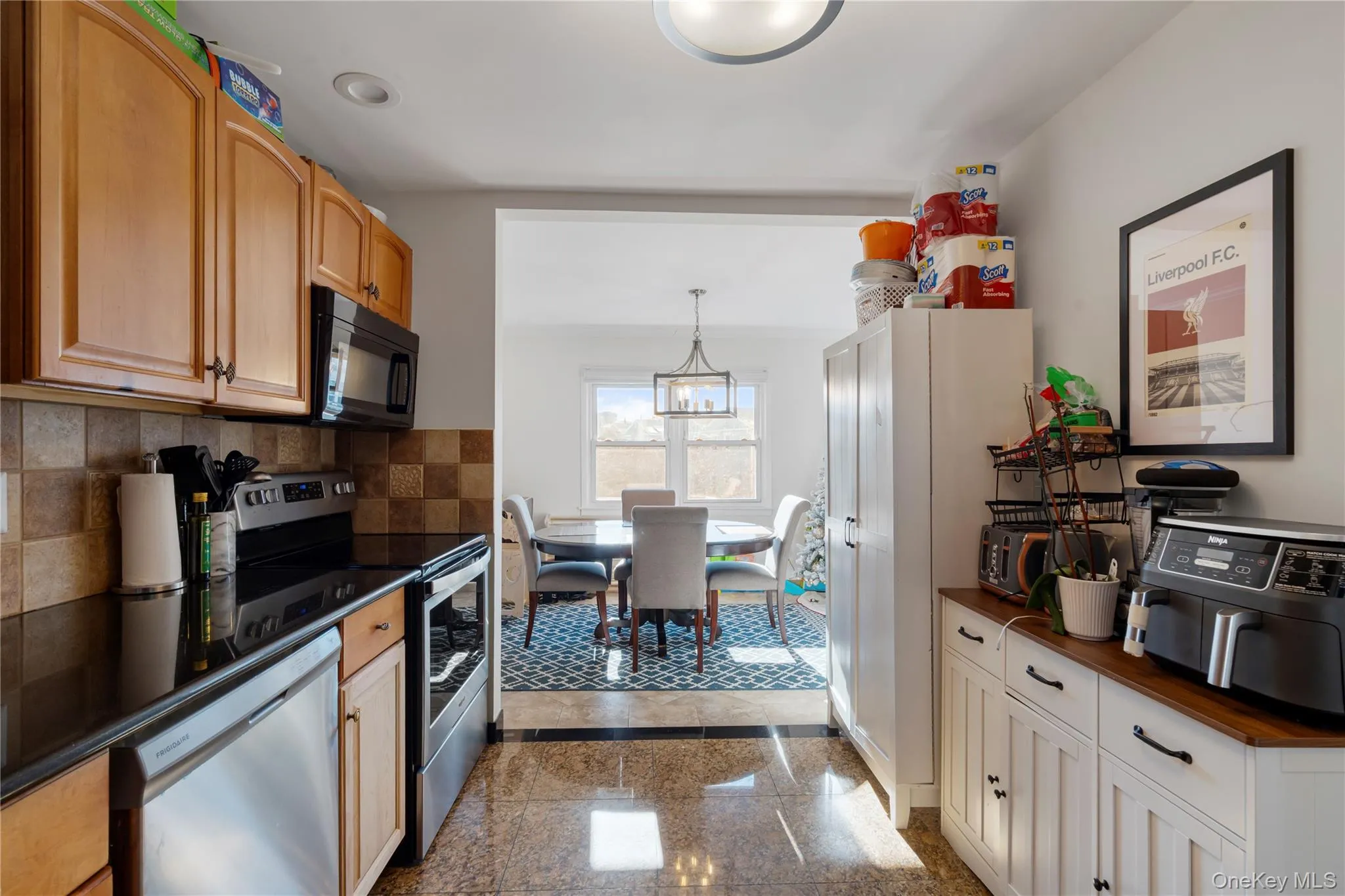 Kitchen with granite floors, stainless steel appliances, hanging light fixtures, tasteful backsplash, and a chandelier Kitchen with granite floors, stainless steel appliances, hanging light fixtures, tasteful backsplash, and a chandelier