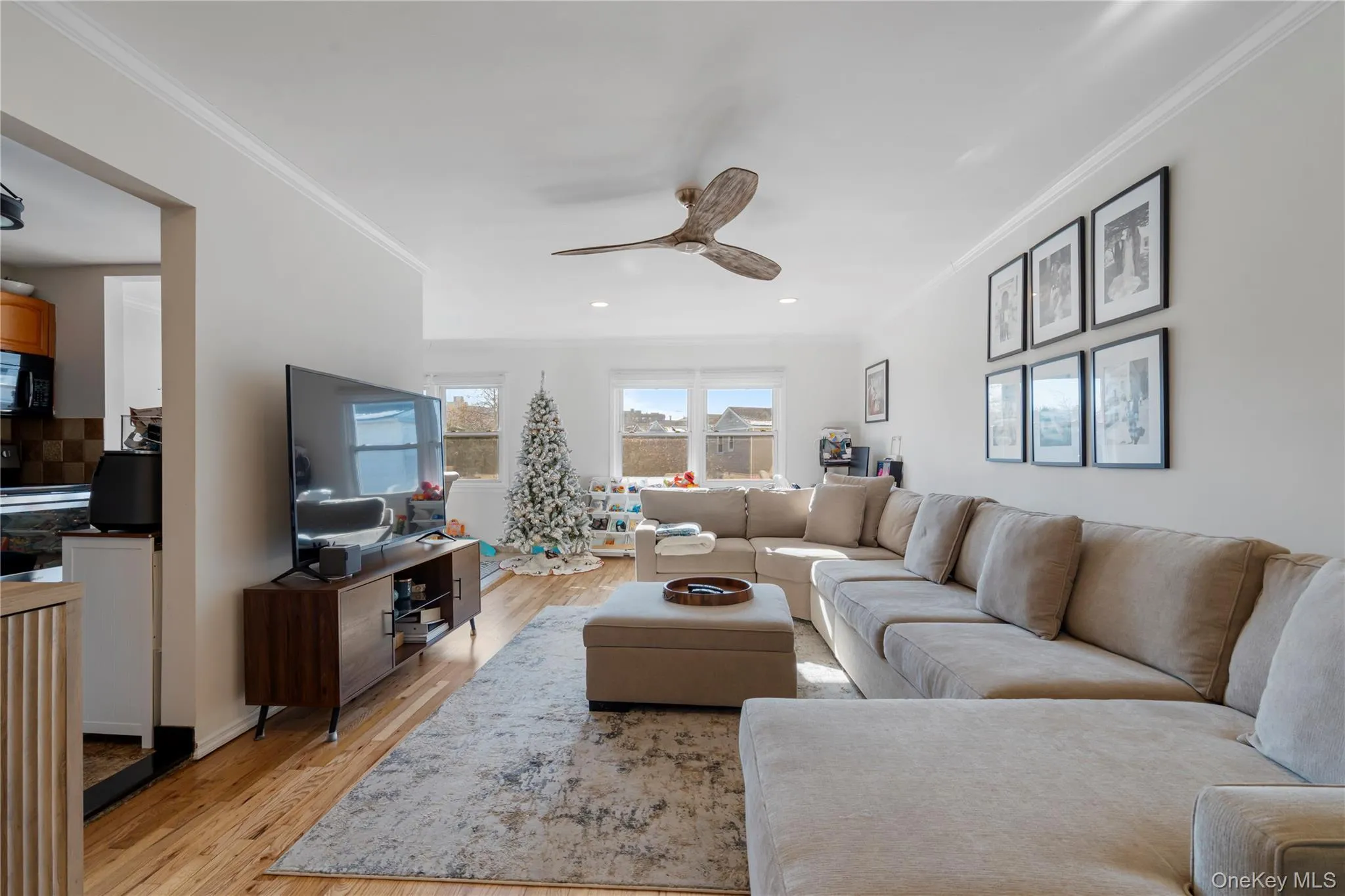 Living area featuring ornamental molding, light wood finished floors, and a ceiling fan Living area featuring ornamental molding, light wood finished floors, and a ceiling fan