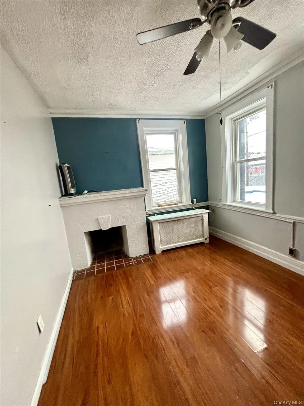 living room featuring wood finished floors, a textured ceiling, a fireplace with flush hearth, and ceiling fan living room featuring wood finished floors, a textured ceiling, a fireplace with flush hearth, and ceiling fan