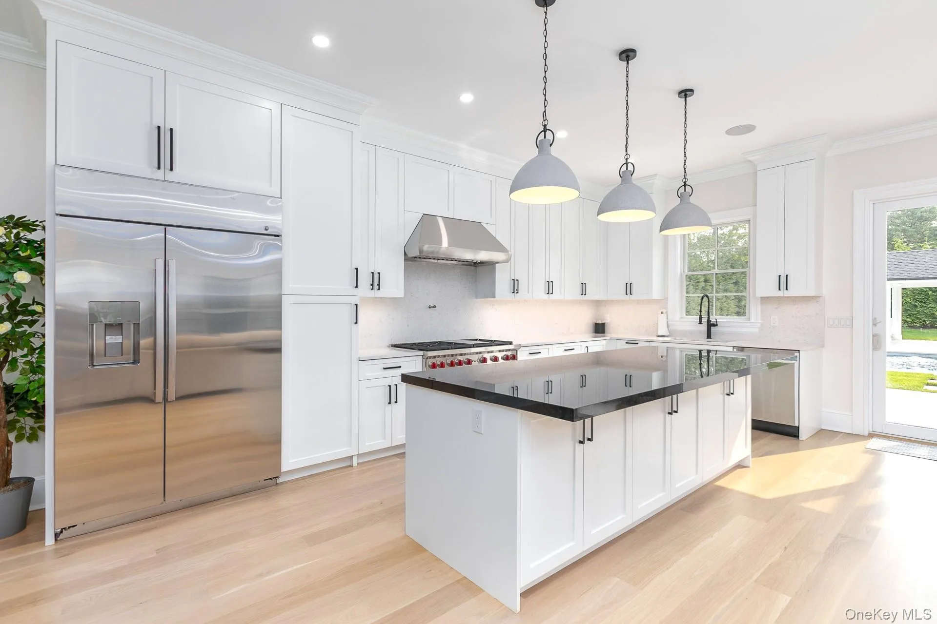 Kitchen with appliances with stainless steel finishes, white cabinetry, crown molding, pendant lighting, and light wood finished floors Kitchen with appliances with stainless steel finishes, white cabinetry, crown molding, pendant lighting, and light wood finished floors