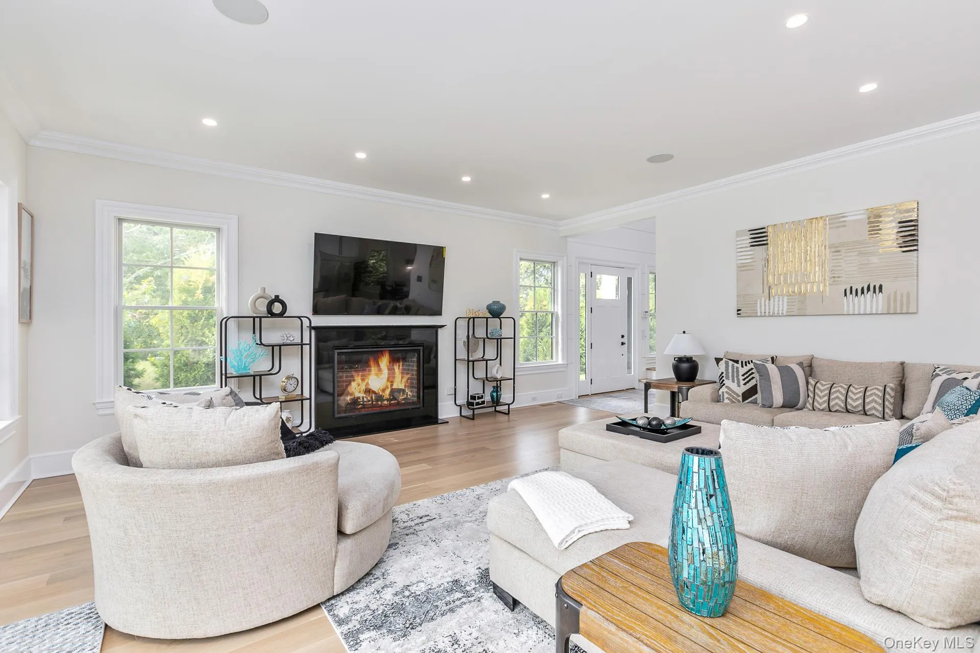Living area with a fireplace with flush hearth, wood finished floors, recessed lighting, and ornamental molding Living area with a fireplace with flush hearth, wood finished floors, recessed lighting, and ornamental molding