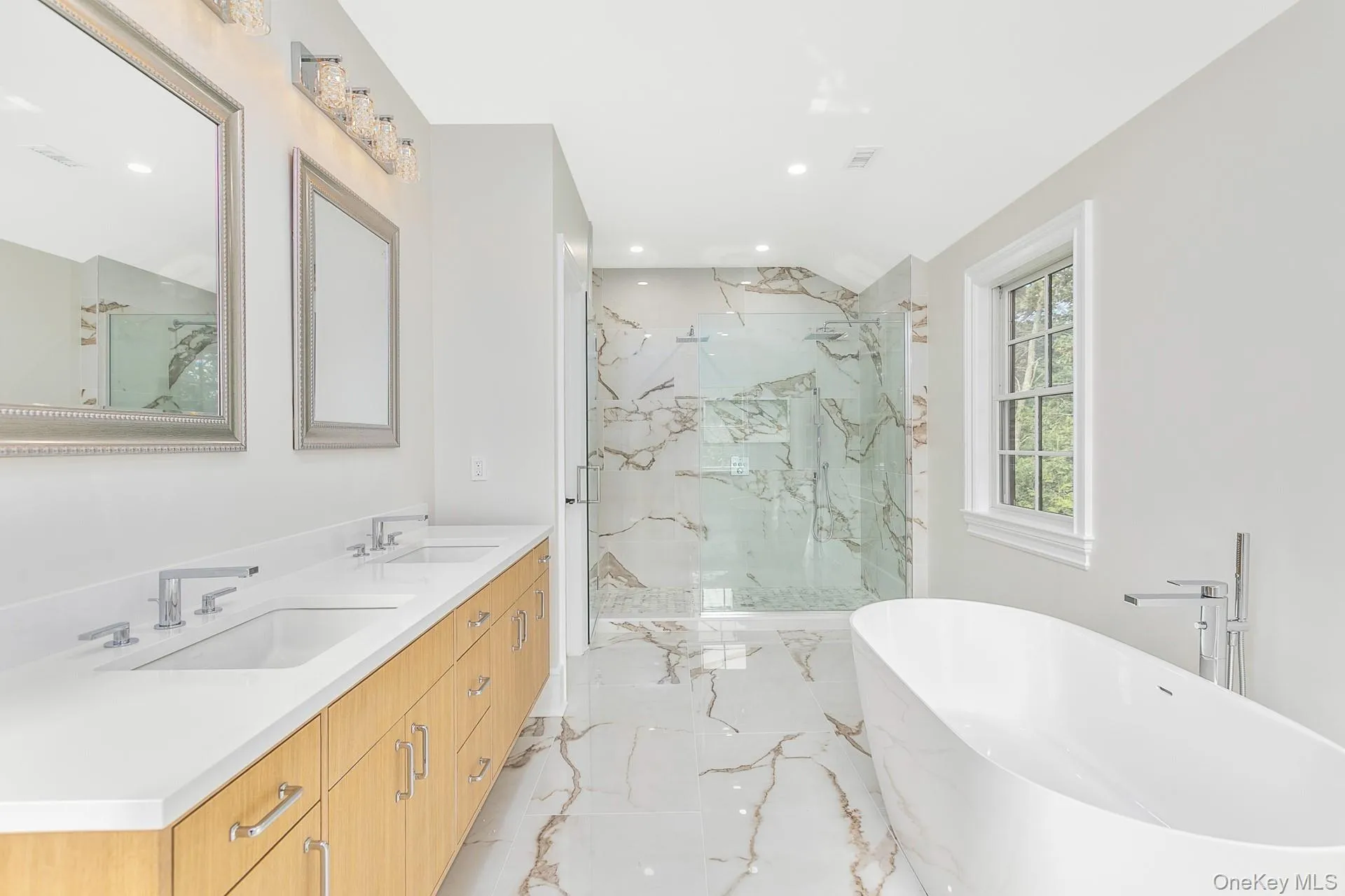 Full bath featuring double vanity, a soaking tub, light marble finish flooring, a marble finish shower, and recessed lighting Full bath featuring double vanity, a soaking tub, light marble finish flooring, a marble finish shower, and recessed lighting