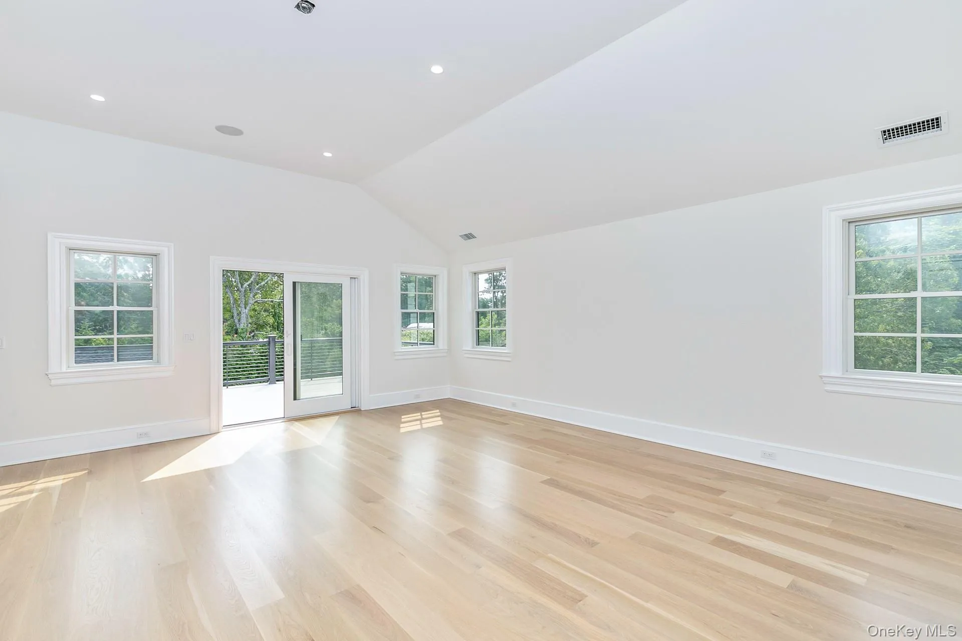 Unfurnished room with light wood-style flooring, vaulted ceiling, and healthy amount of natural light Unfurnished room with light wood-style flooring, vaulted ceiling, and healthy amount of natural light