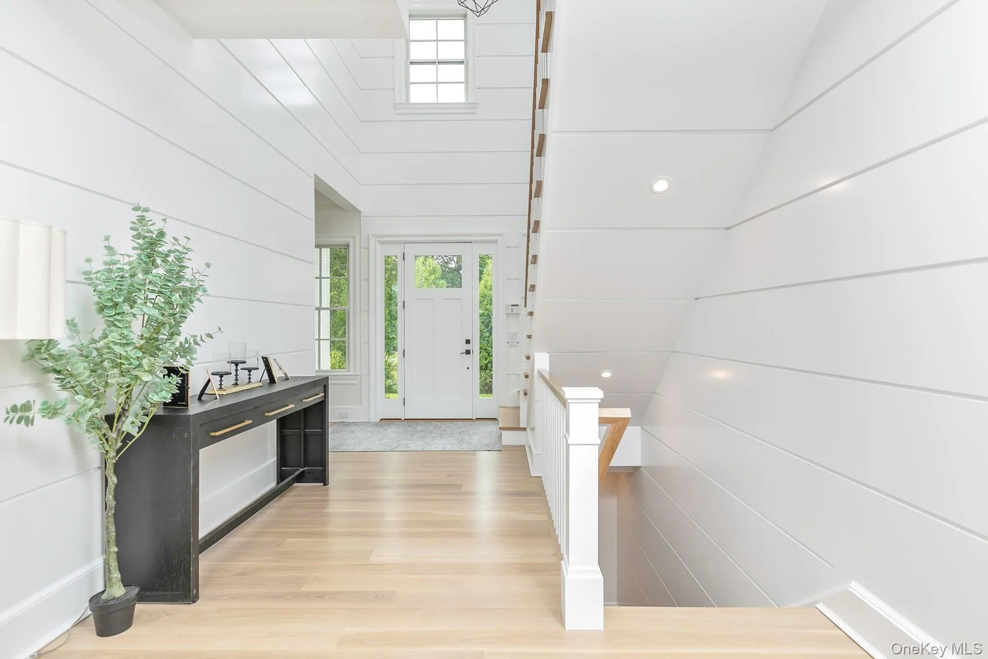 Foyer with light wood-style flooring and wooden walls Foyer with light wood-style flooring and wooden walls