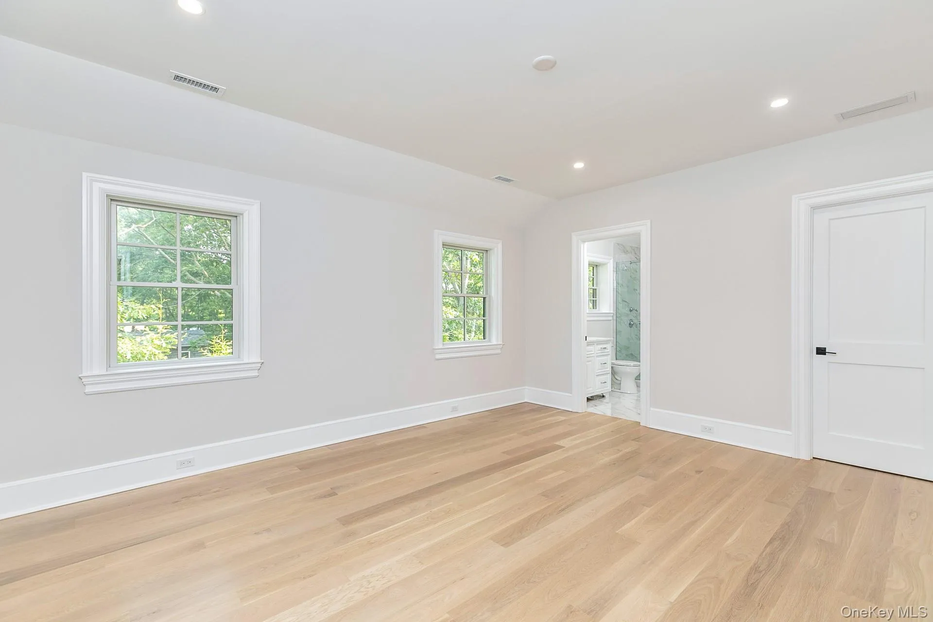 Unfurnished bedroom with light wood-style floors, recessed lighting, ensuite bath, and lofted ceiling Unfurnished bedroom with light wood-style floors, recessed lighting, ensuite bath, and lofted ceiling