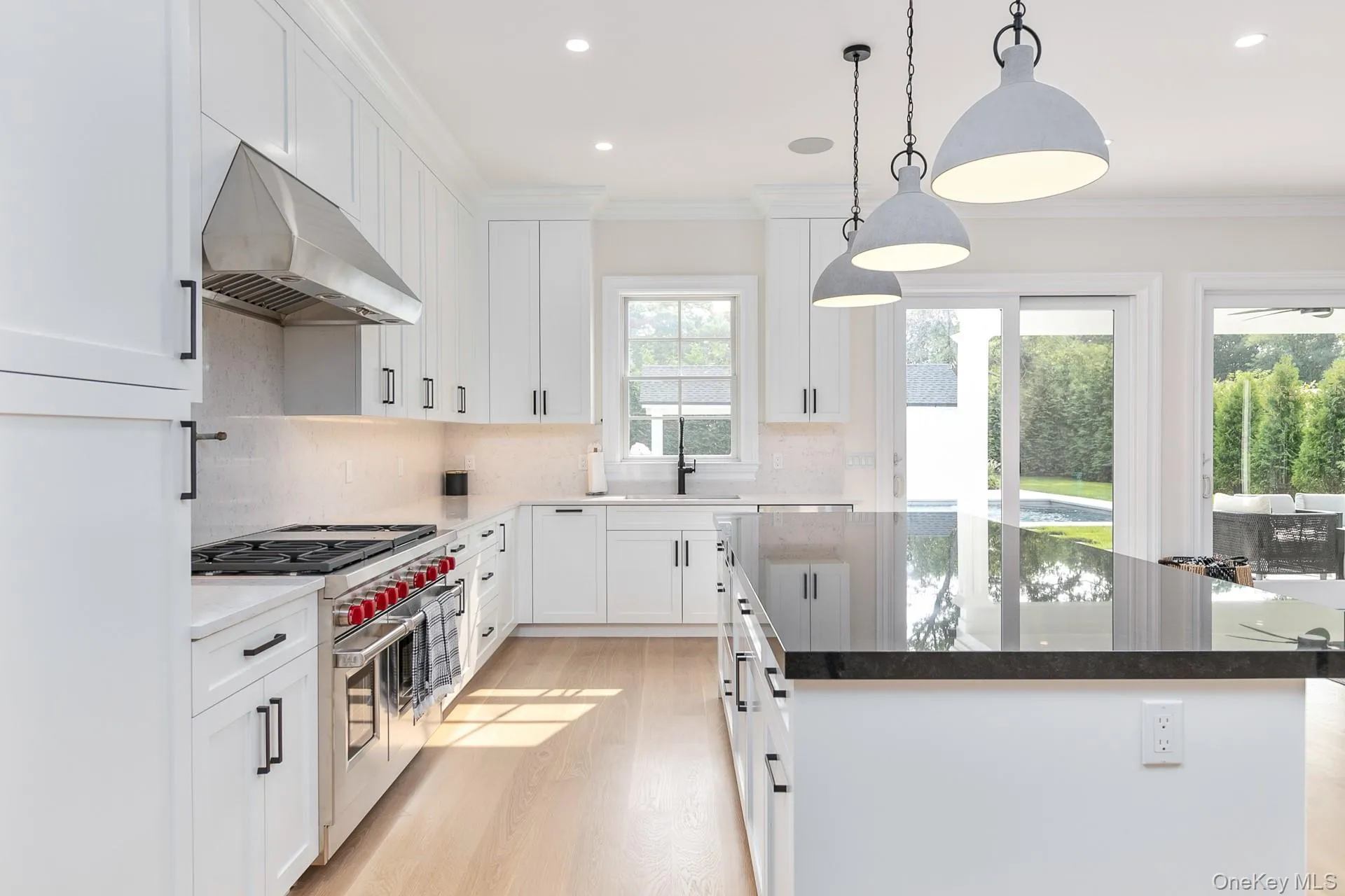 Kitchen featuring dark stone countertops, double oven range, decorative light fixtures, white cabinets, and ornamental molding Kitchen featuring dark stone countertops, double oven range, decorative light fixtures, white cabinets, and ornamental molding