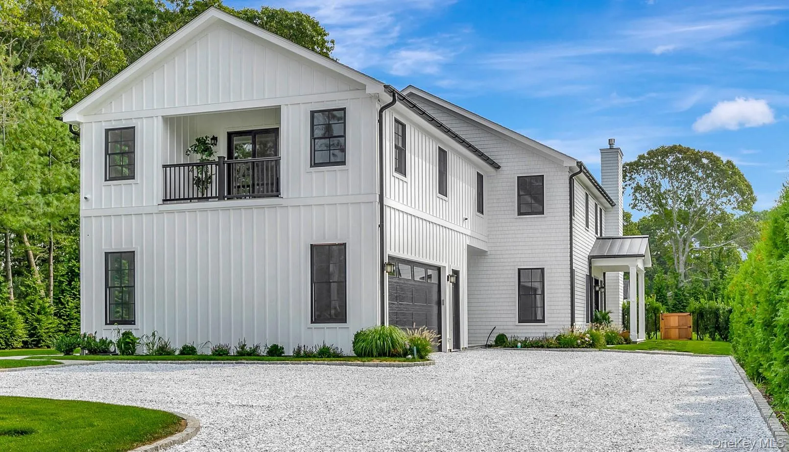 Modern farmhouse with a balcony, a chimney, driveway, and board and batten siding Modern farmhouse with a balcony, a chimney, driveway, and board and batten siding