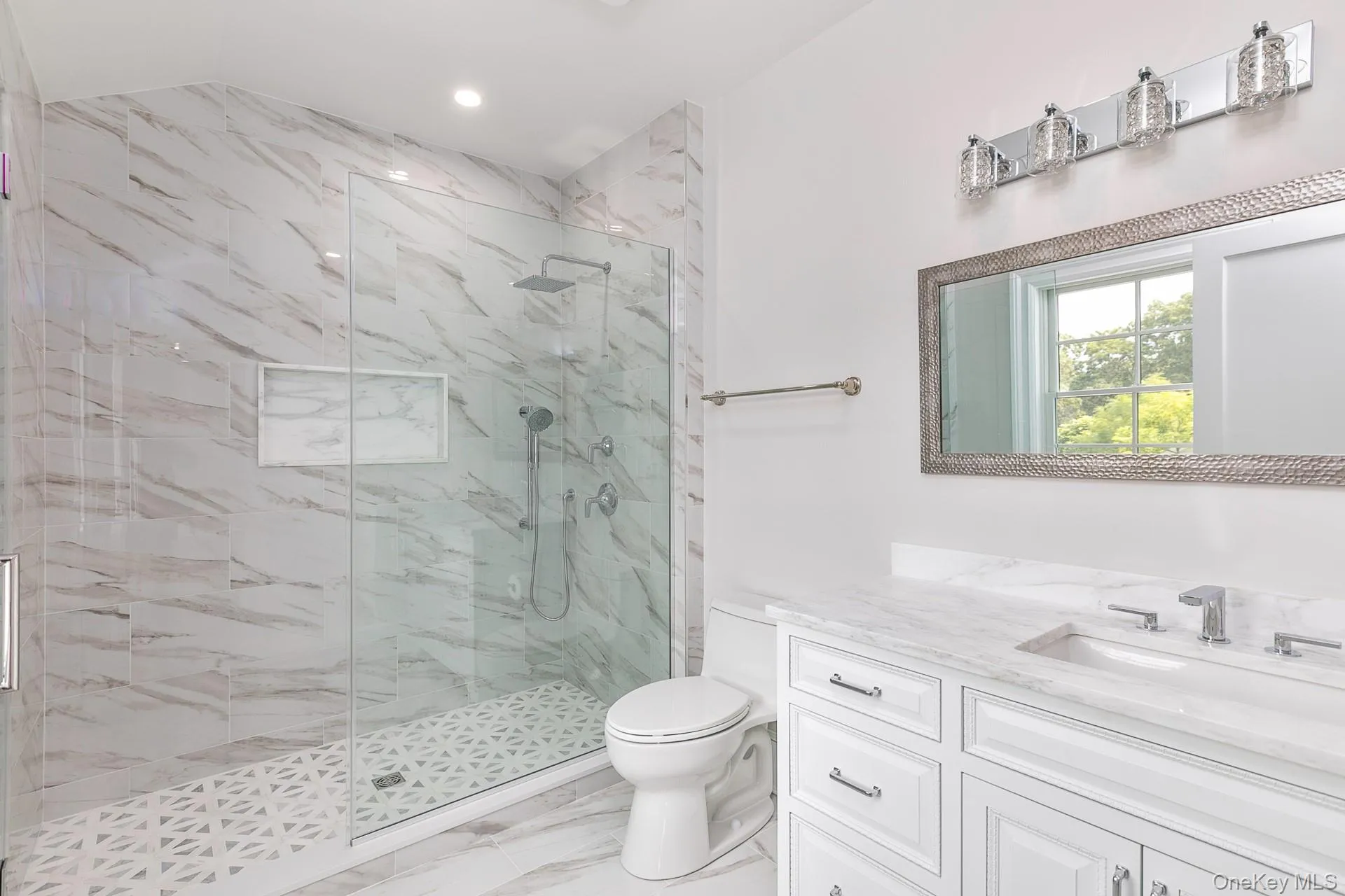 Bathroom with a marble finish shower, light marble finish flooring, vanity, and recessed lighting Bathroom with a marble finish shower, light marble finish flooring, vanity, and recessed lighting