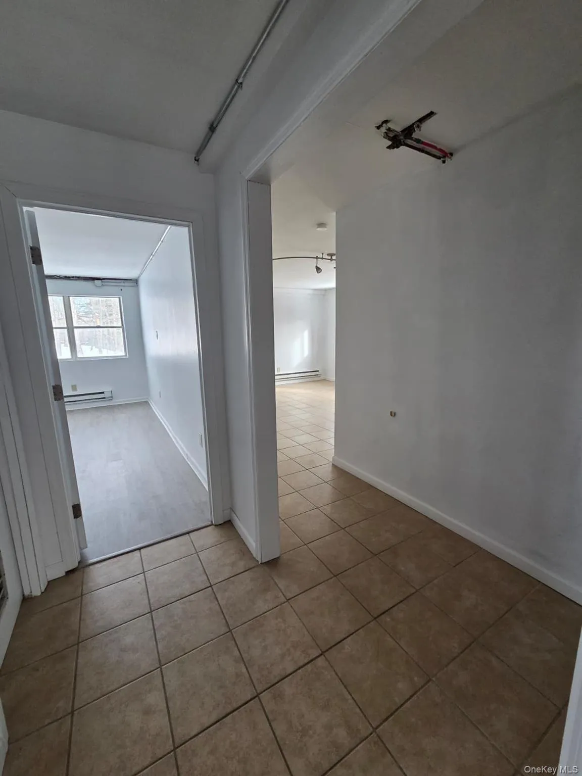 Hall with tile patterned floors and a baseboard heating unit Hall with tile patterned floors and a baseboard heating unit