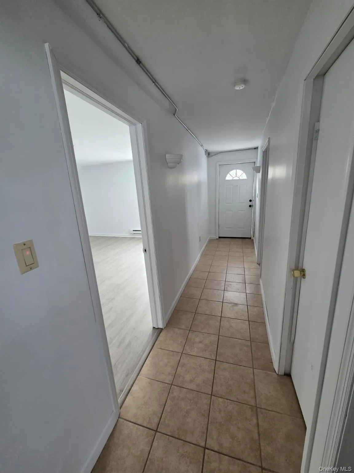 Hallway with light tile patterned floors and baseboards Hallway with light tile patterned floors and baseboards