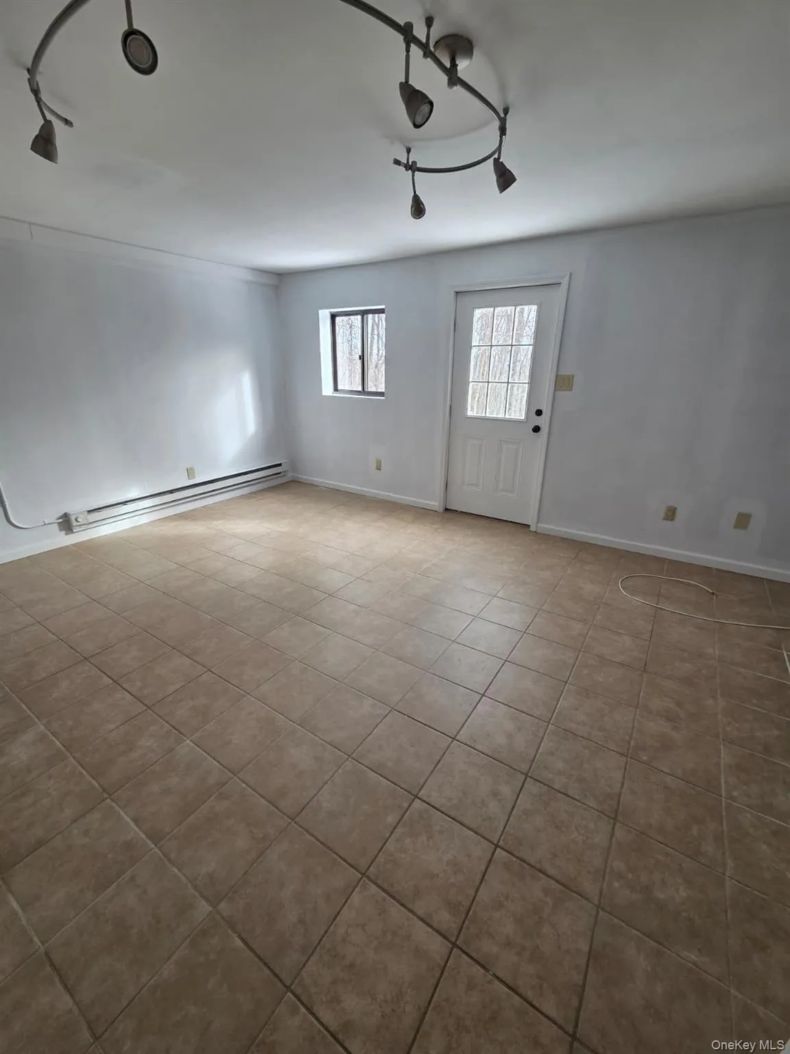 Unfurnished room with rail lighting, a baseboard radiator, and light tile patterned floors Unfurnished room with rail lighting, a baseboard radiator, and light tile patterned floors