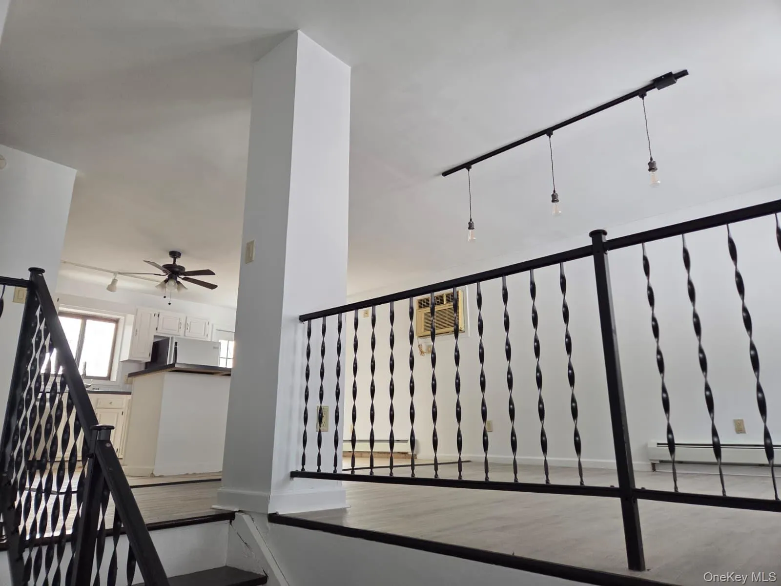 Staircase with a ceiling fan, a baseboard heating unit, and track lighting Staircase with a ceiling fan, a baseboard heating unit, and track lighting