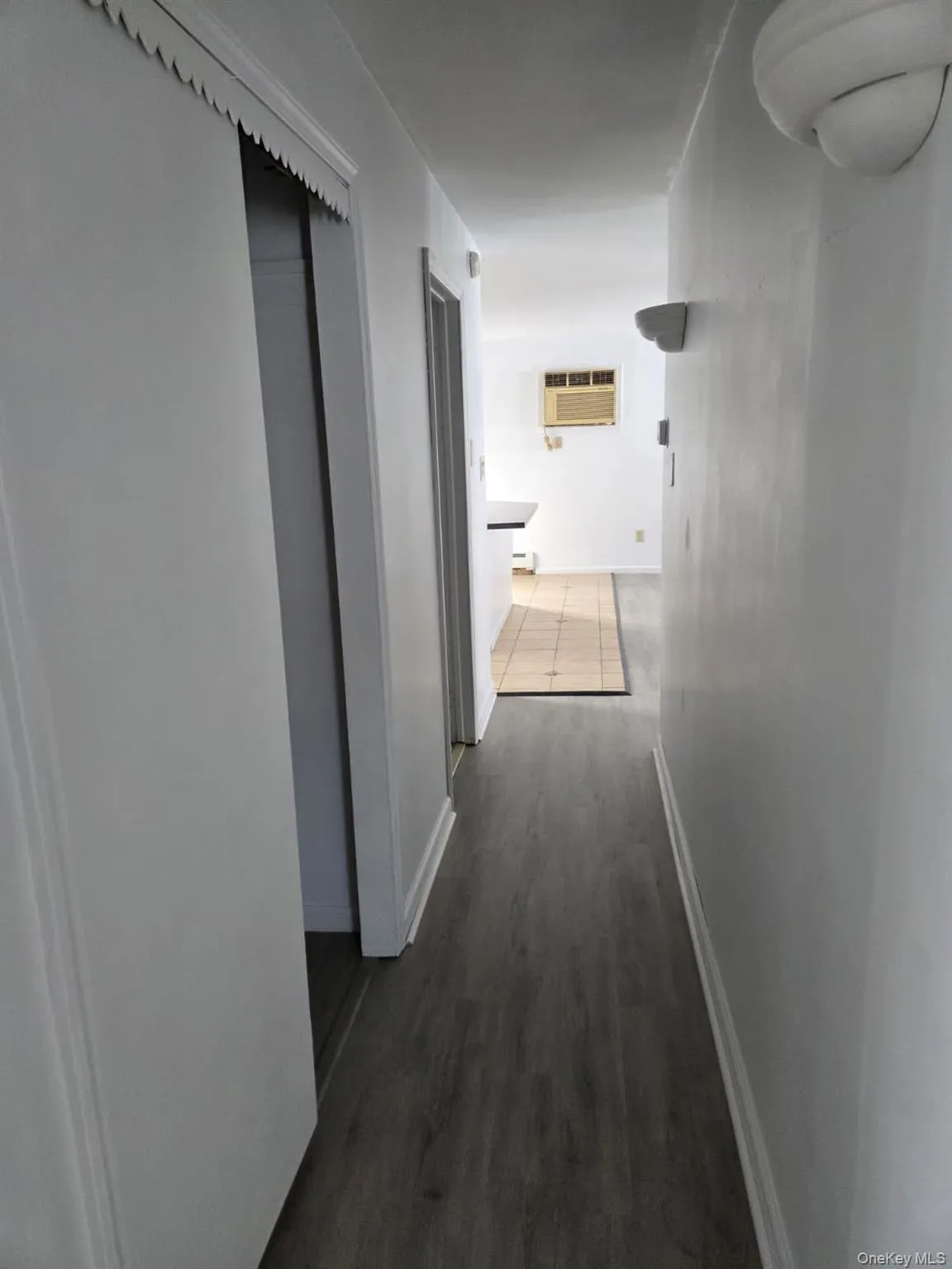 Hallway featuring baseboards and dark wood-style flooring Hallway featuring baseboards and dark wood-style flooring