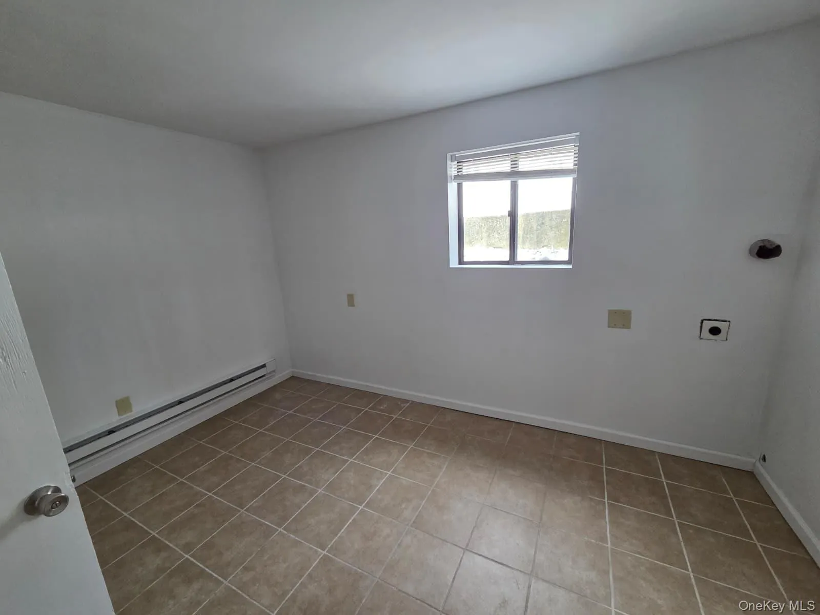 Unfurnished room featuring a baseboard heating unit and light tile patterned floors Unfurnished room featuring a baseboard heating unit and light tile patterned floors