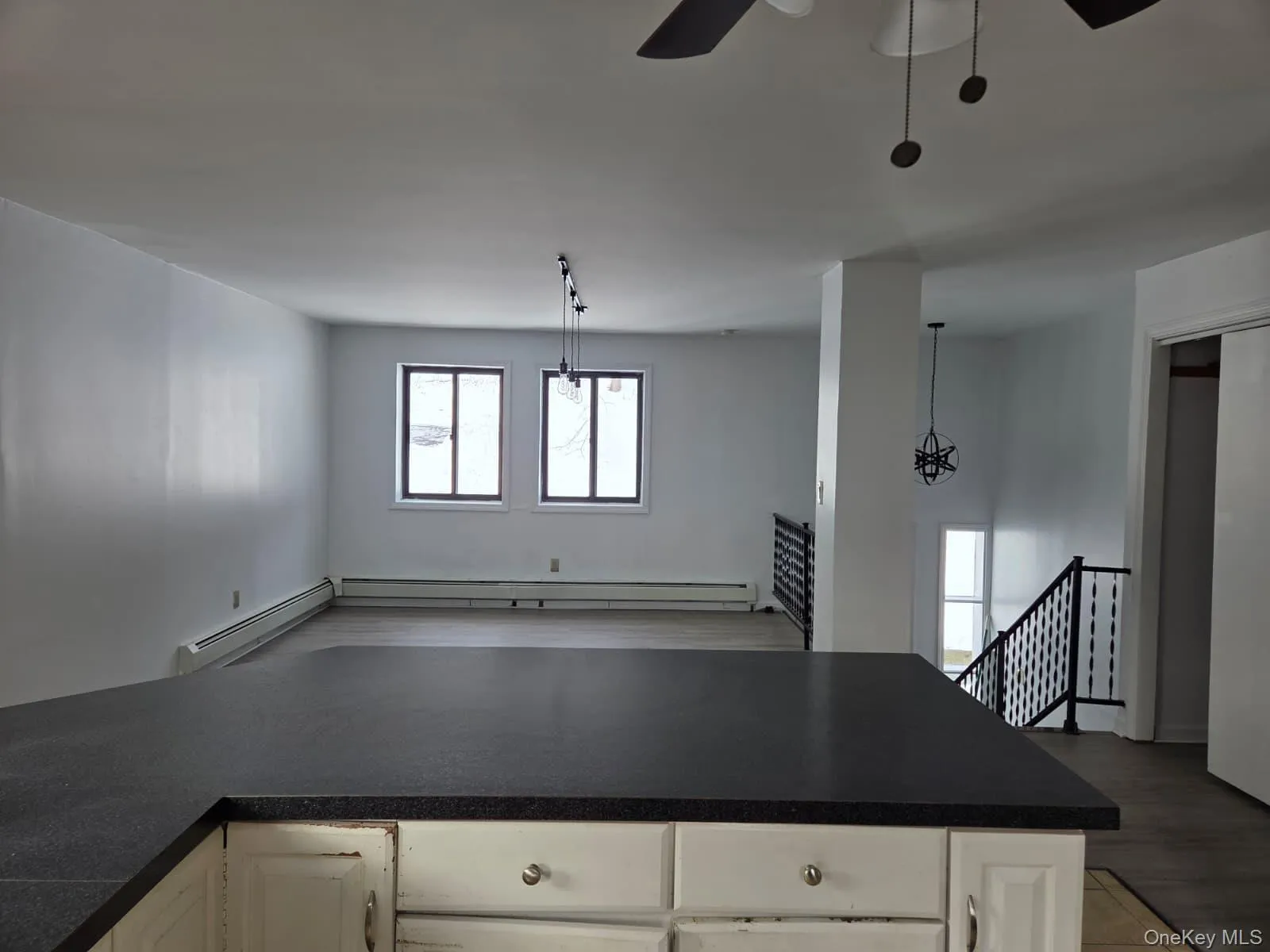 Kitchen with open floor plan, ceiling fan, hanging light fixtures, and a baseboard radiator Kitchen with open floor plan, ceiling fan, hanging light fixtures, and a baseboard radiator