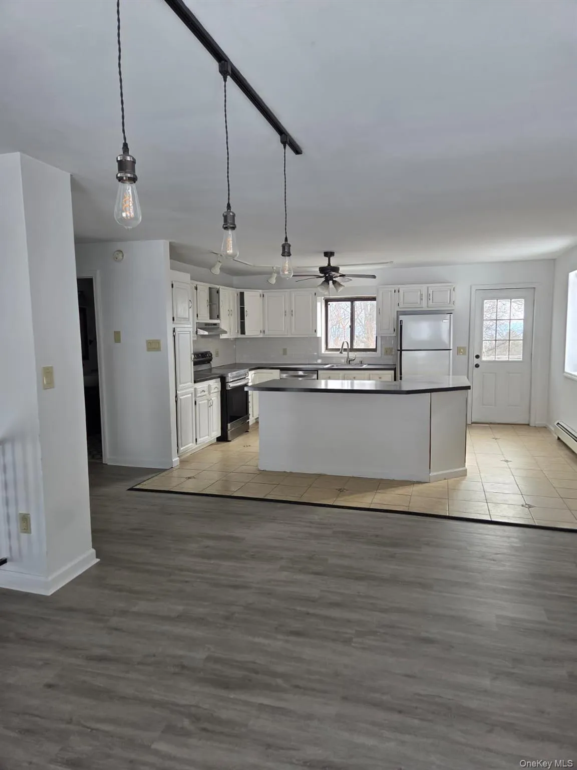 Kitchen with dark countertops, a kitchen island, appliances with stainless steel finishes, and white cabinets Kitchen with dark countertops, a kitchen island, appliances with stainless steel finishes, and white cabinets