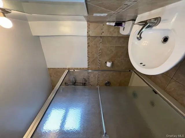 Full bath with tile walls, tile patterned floors, and a stall shower Full bath with tile walls, tile patterned floors, and a stall shower