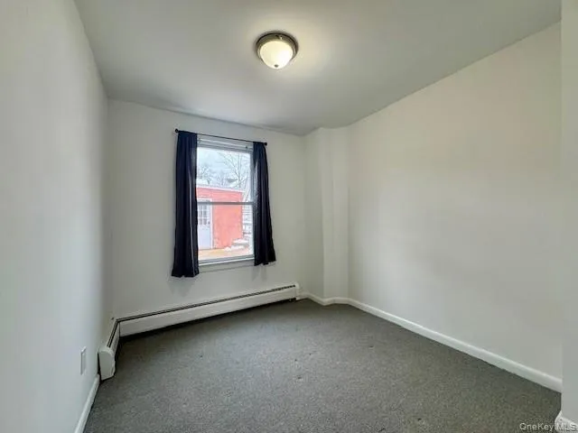 Unfurnished room featuring carpet flooring and baseboard heating Unfurnished room featuring carpet flooring and baseboard heating