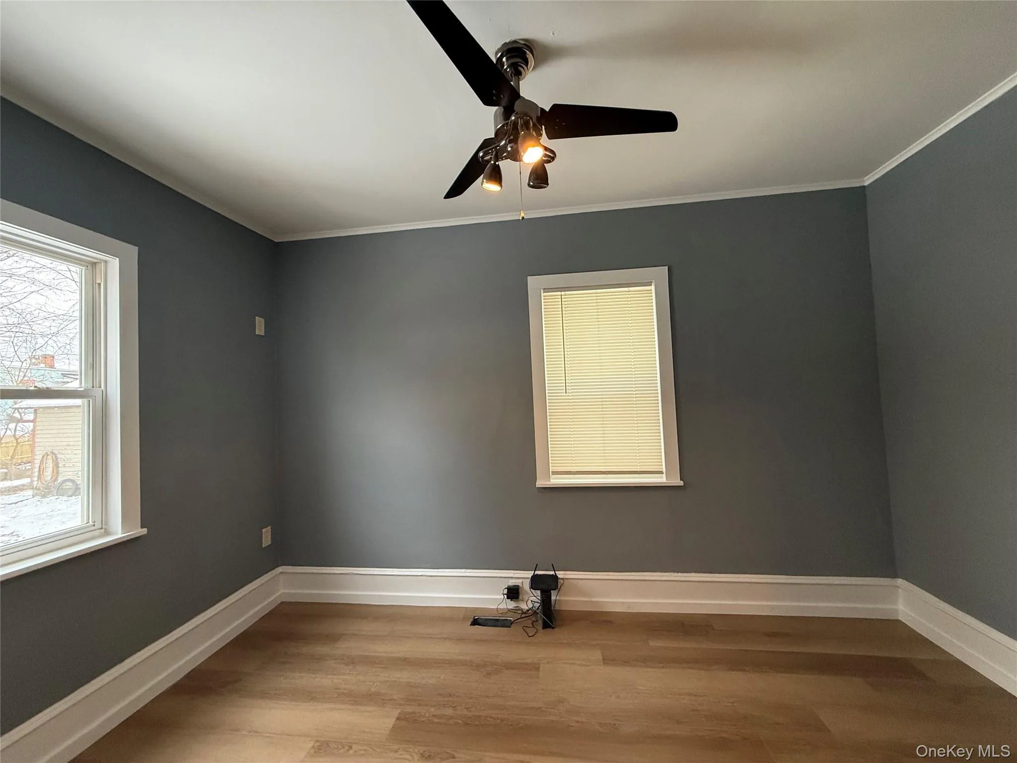 Unfurnished room featuring light wood-style flooring, ornamental molding, and a ceiling fan Unfurnished room featuring light wood-style flooring, ornamental molding, and a ceiling fan