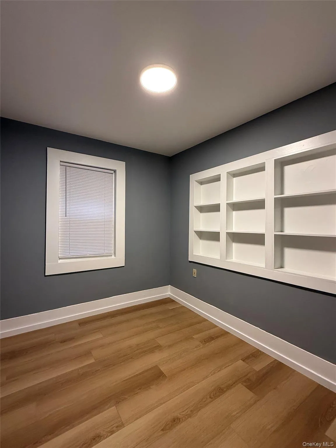 Unfurnished room featuring built in features and light wood-style floors Unfurnished room featuring built in features and light wood-style floors