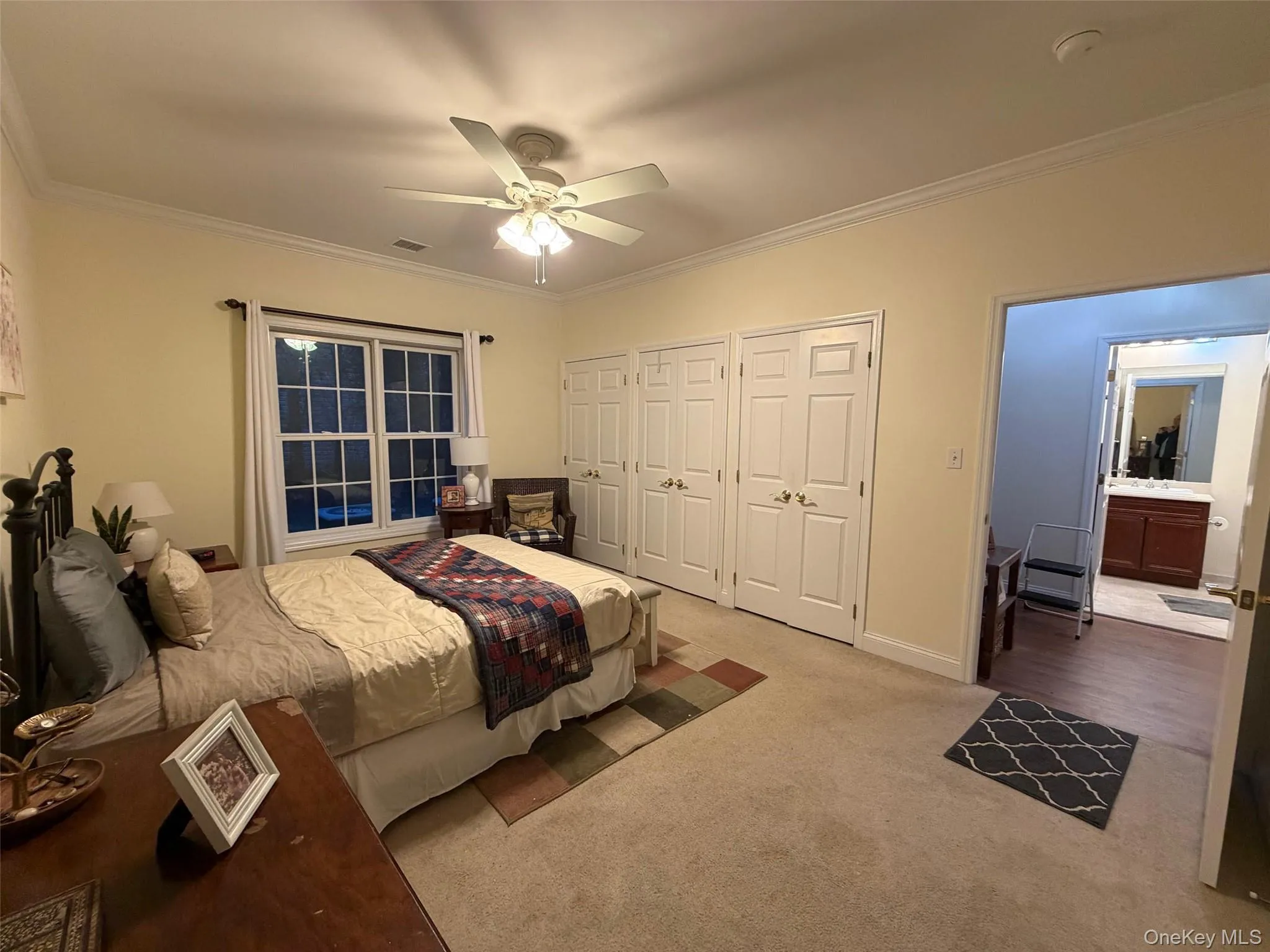Bedroom featuring two closets, crown molding, carpet, and a ceiling fan Bedroom featuring two closets, crown molding, carpet, and a ceiling fan