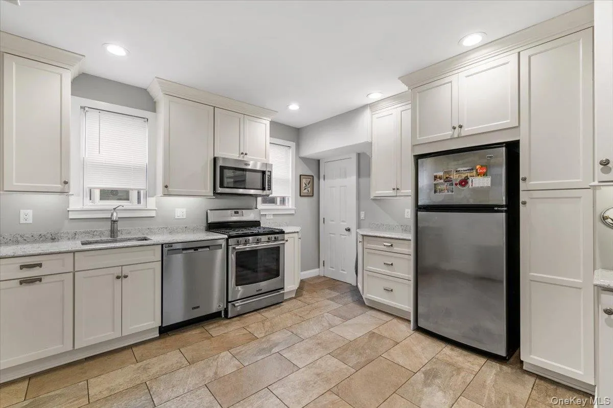 Kitchen with appliances with stainless steel finishes, white cabinets, light stone counters, and recessed lighting Kitchen with appliances with stainless steel finishes, white cabinets, light stone counters, and recessed lighting