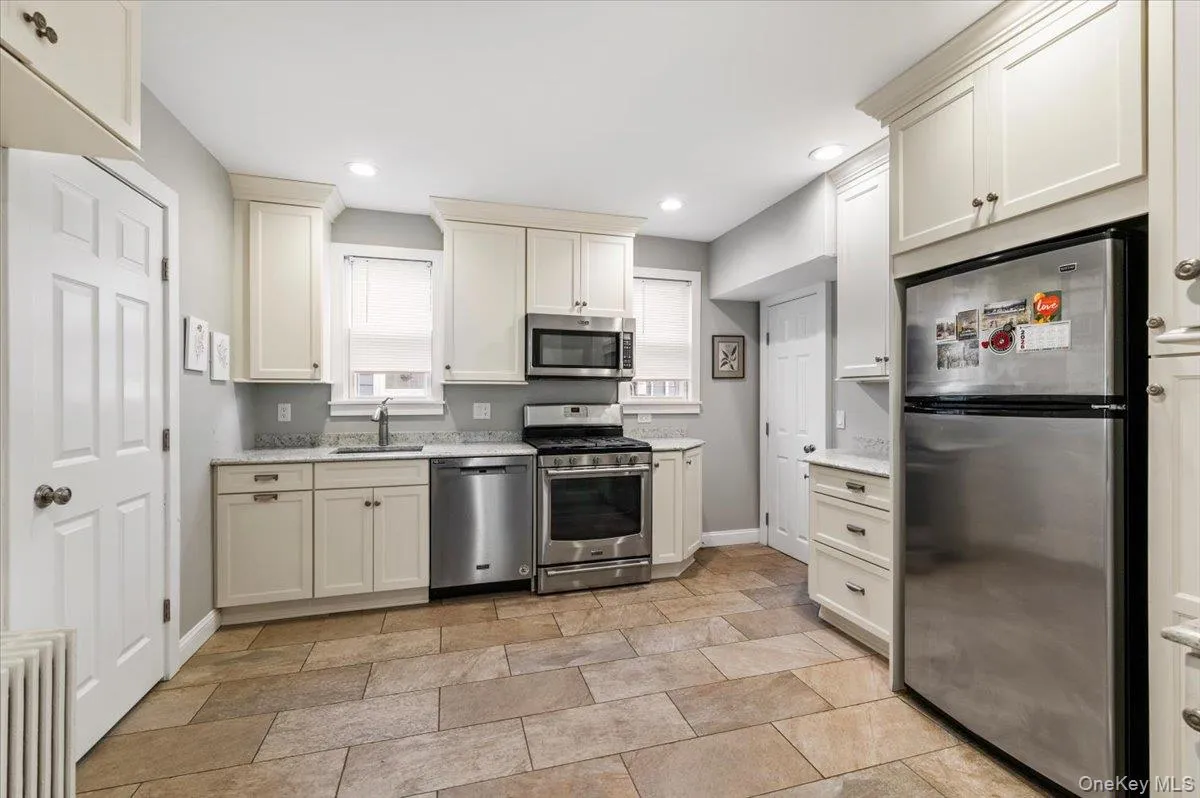 Kitchen with stainless steel appliances, radiator heating unit, stone finish flooring, recessed lighting, and light stone countertops Kitchen with stainless steel appliances, radiator heating unit, stone finish flooring, recessed lighting, and light stone countertops