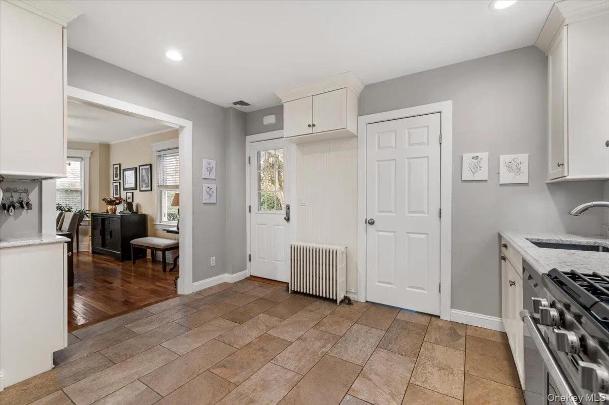 Kitchen featuring light stone countertops, radiator, white cabinetry, healthy amount of natural light, and recessed lighting Kitchen featuring light stone countertops, radiator, white cabinetry, healthy amount of natural light, and recessed lighting