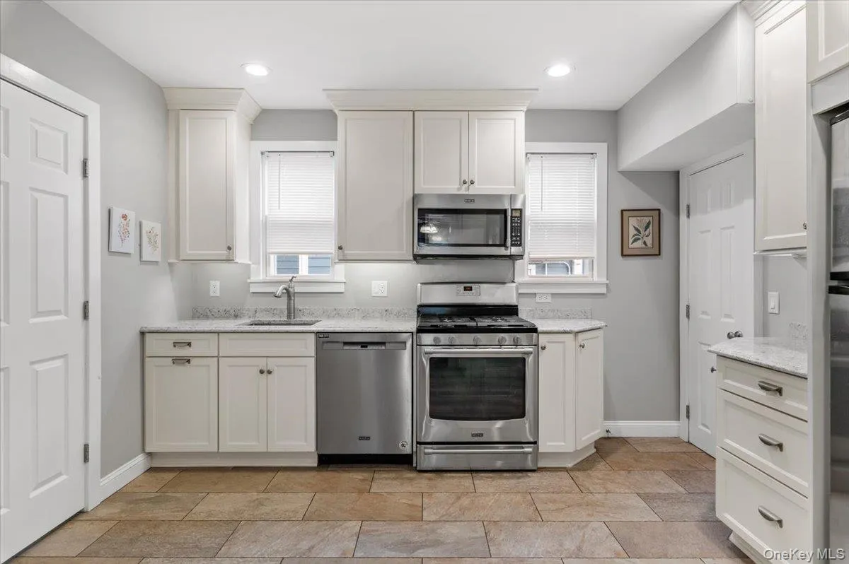 Kitchen with stainless steel appliances, healthy amount of natural light, white cabinetry, light stone countertops, and recessed lighting Kitchen with stainless steel appliances, healthy amount of natural light, white cabinetry, light stone countertops, and recessed lighting