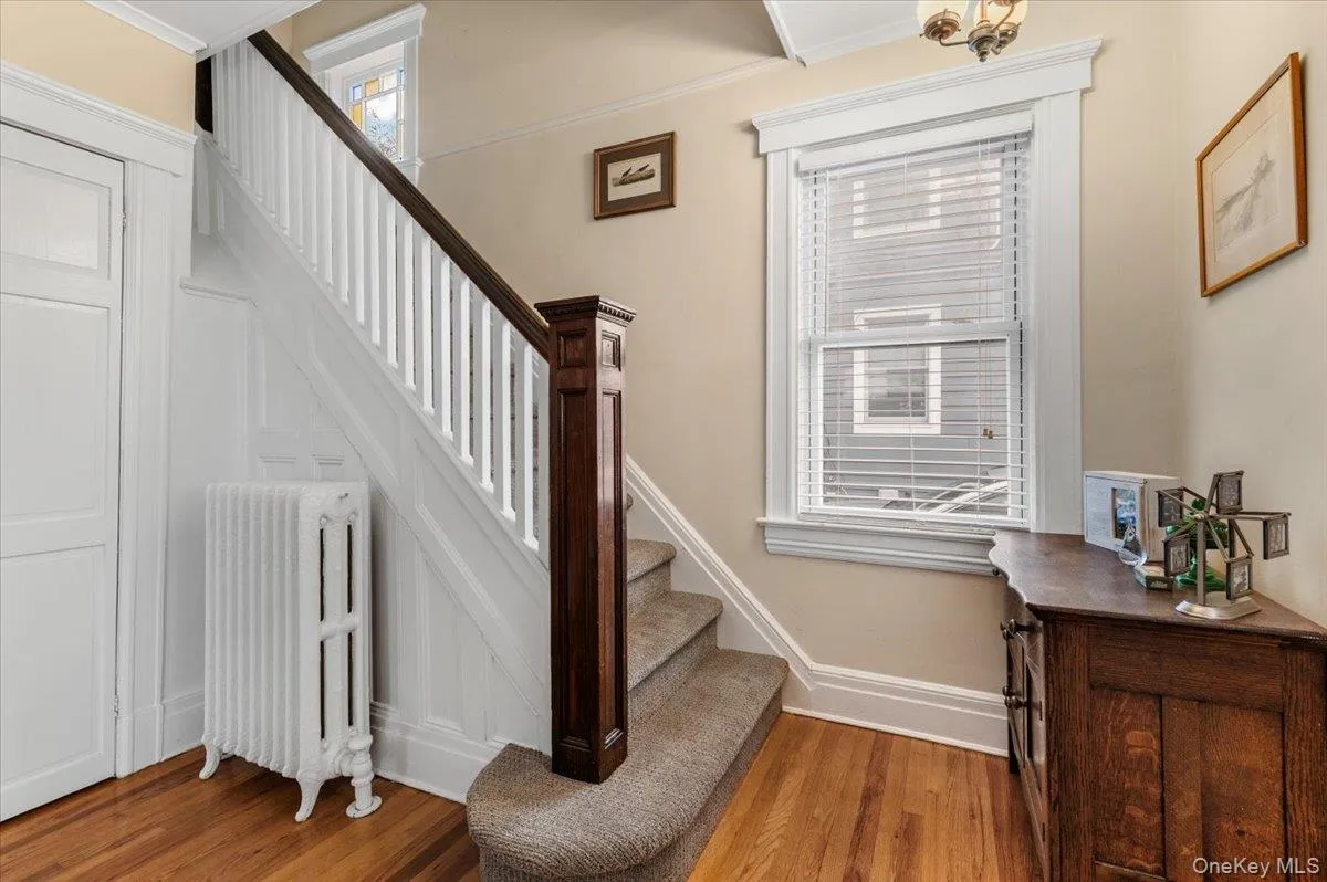 Stairs with radiator heating unit, wood finished floors, ornamental molding, and healthy amount of natural light Stairs with radiator heating unit, wood finished floors, ornamental molding, and healthy amount of natural light