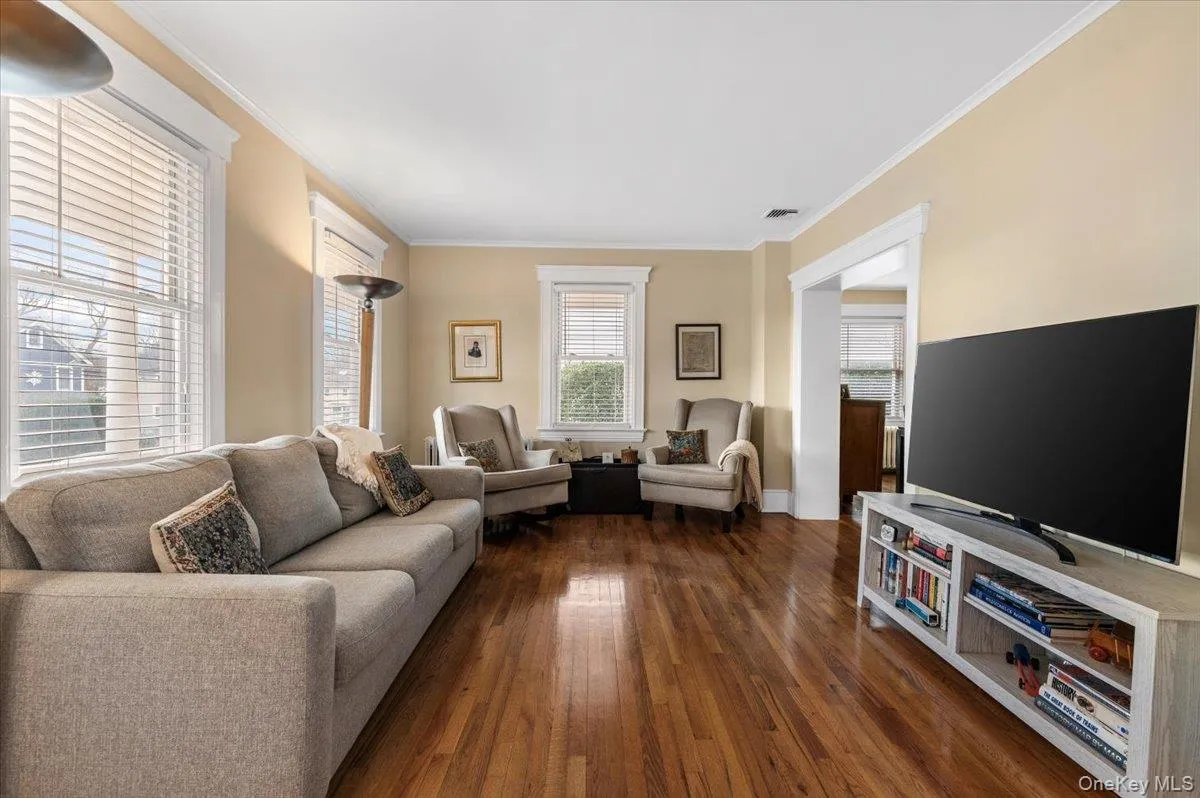 Living area featuring ornamental molding and dark wood-style flooring Living area featuring ornamental molding and dark wood-style flooring