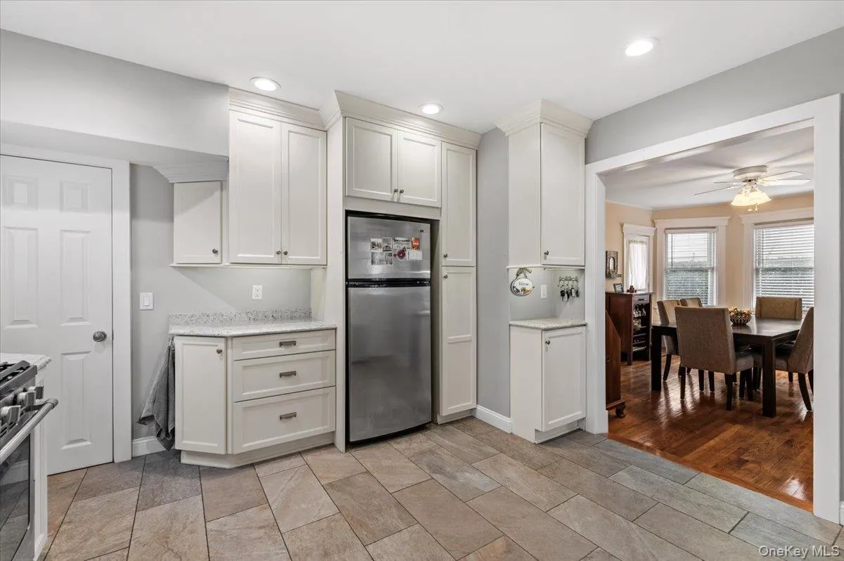 Kitchen with stainless steel appliances, white cabinetry, light stone countertops, ceiling fan, and recessed lighting Kitchen with stainless steel appliances, white cabinetry, light stone countertops, ceiling fan, and recessed lighting