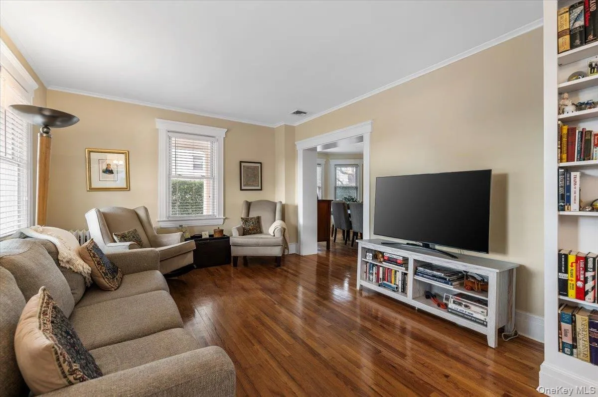 Living area featuring ornamental molding, dark wood-style flooring, and healthy amount of natural light Living area featuring ornamental molding, dark wood-style flooring, and healthy amount of natural light