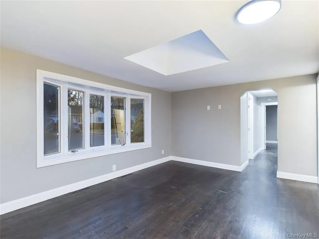 Unfurnished room with dark wood-type flooring and arched walkways Unfurnished room with dark wood-type flooring and arched walkways