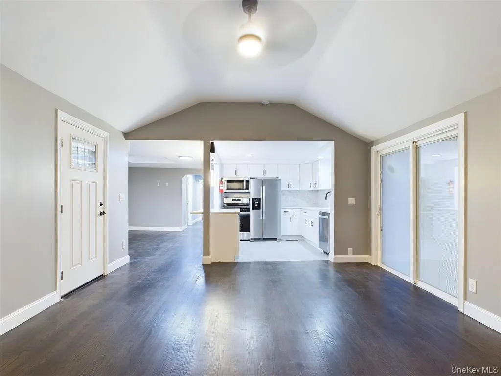 Kitchen with open floor plan, appliances with stainless steel finishes, white cabinets, dark wood finished floors, and lofted ceiling Kitchen with open floor plan, appliances with stainless steel finishes, white cabinets, dark wood finished floors, and lofted ceiling
