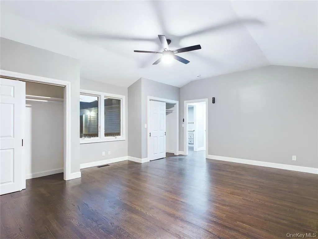 Unfurnished bedroom featuring two closets, dark wood-type flooring, a ceiling fan, and lofted ceiling Unfurnished bedroom featuring two closets, dark wood-type flooring, a ceiling fan, and lofted ceiling