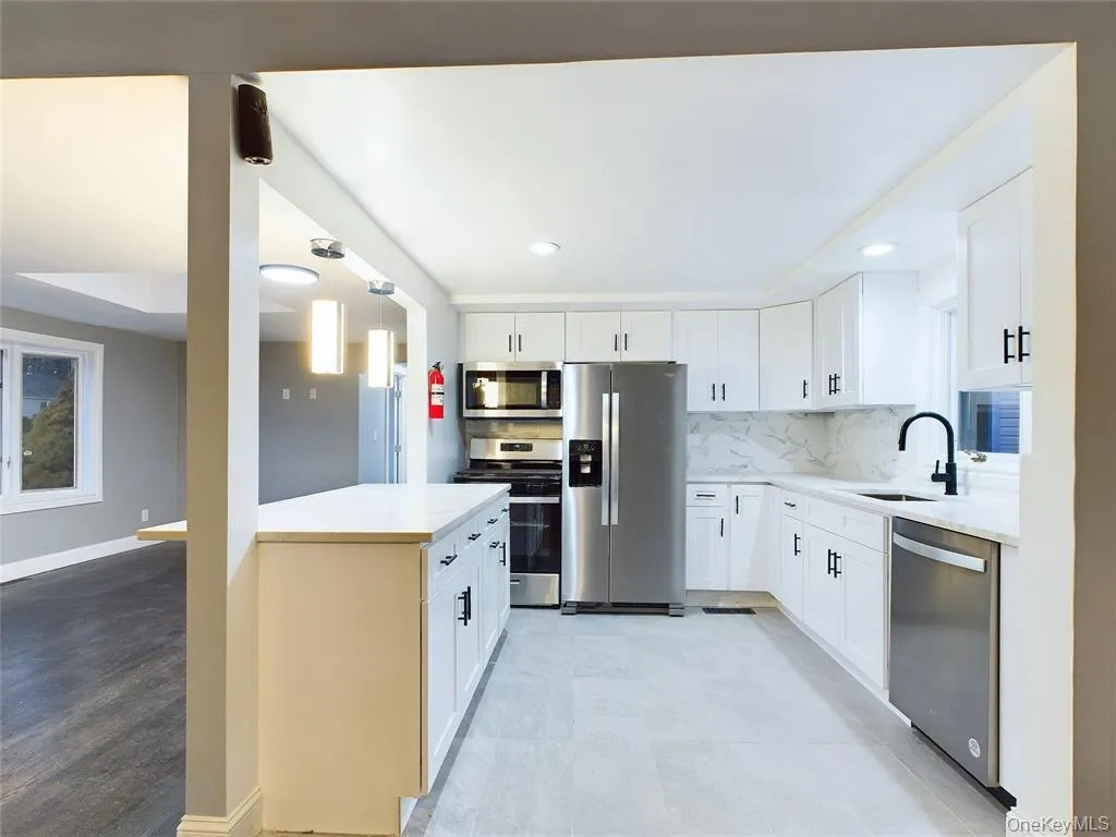 Kitchen featuring appliances with stainless steel finishes, white cabinetry, tasteful backsplash, light stone counters, and recessed lighting Kitchen featuring appliances with stainless steel finishes, white cabinetry, tasteful backsplash, light stone counters, and recessed lighting