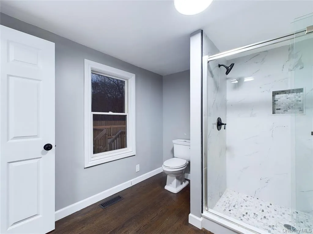 Bathroom featuring a marble finish shower and dark wood-type flooring Bathroom featuring a marble finish shower and dark wood-type flooring