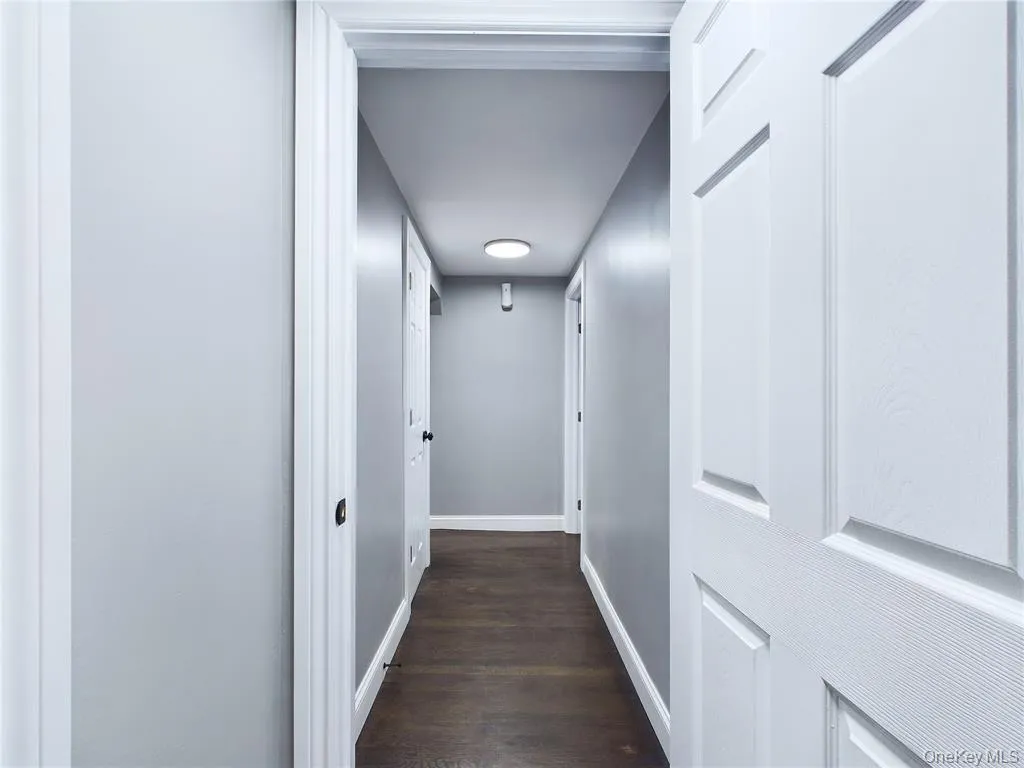 Corridor featuring baseboards and dark wood-type flooring Corridor featuring baseboards and dark wood-type flooring