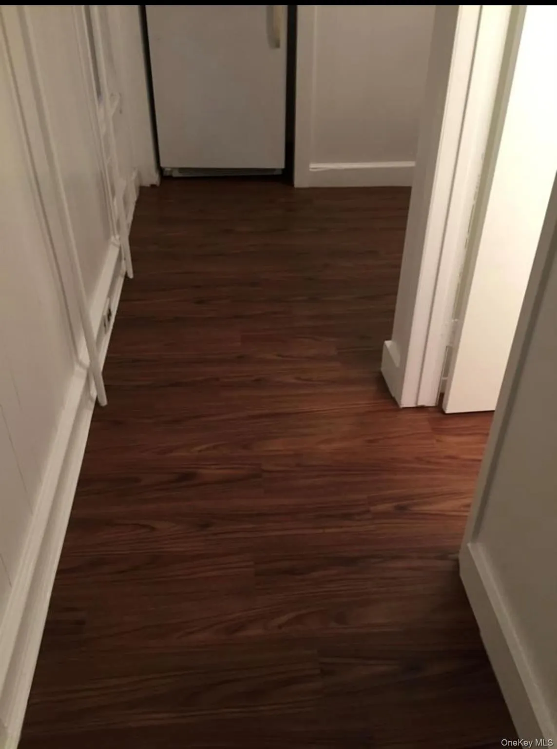 Corridor featuring dark wood-type flooring and baseboards Corridor featuring dark wood-type flooring and baseboards
