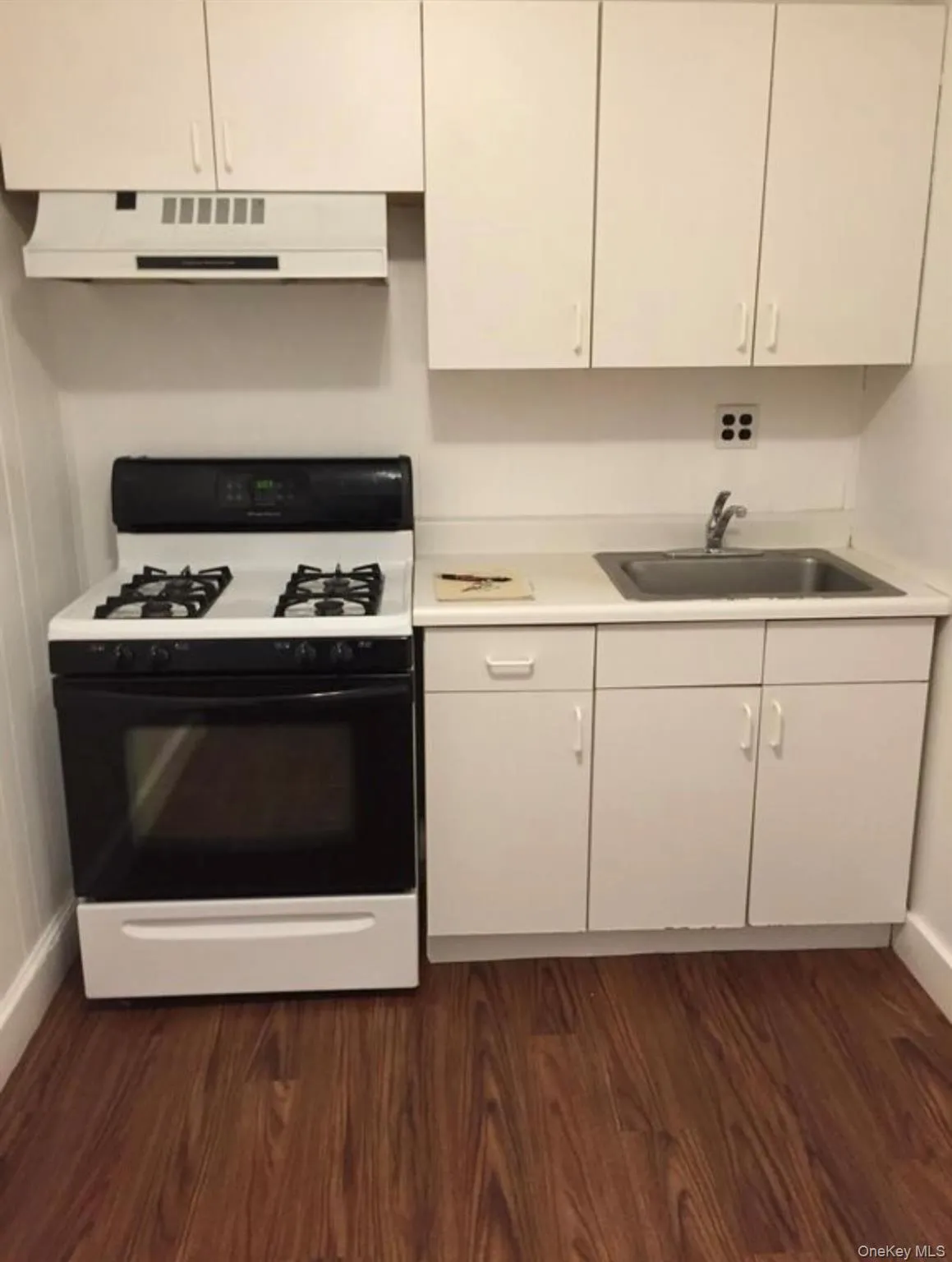Kitchen featuring range with gas stovetop, light countertops, extractor fan, and dark wood-style flooring Kitchen featuring range with gas stovetop, light countertops, extractor fan, and dark wood-style flooring