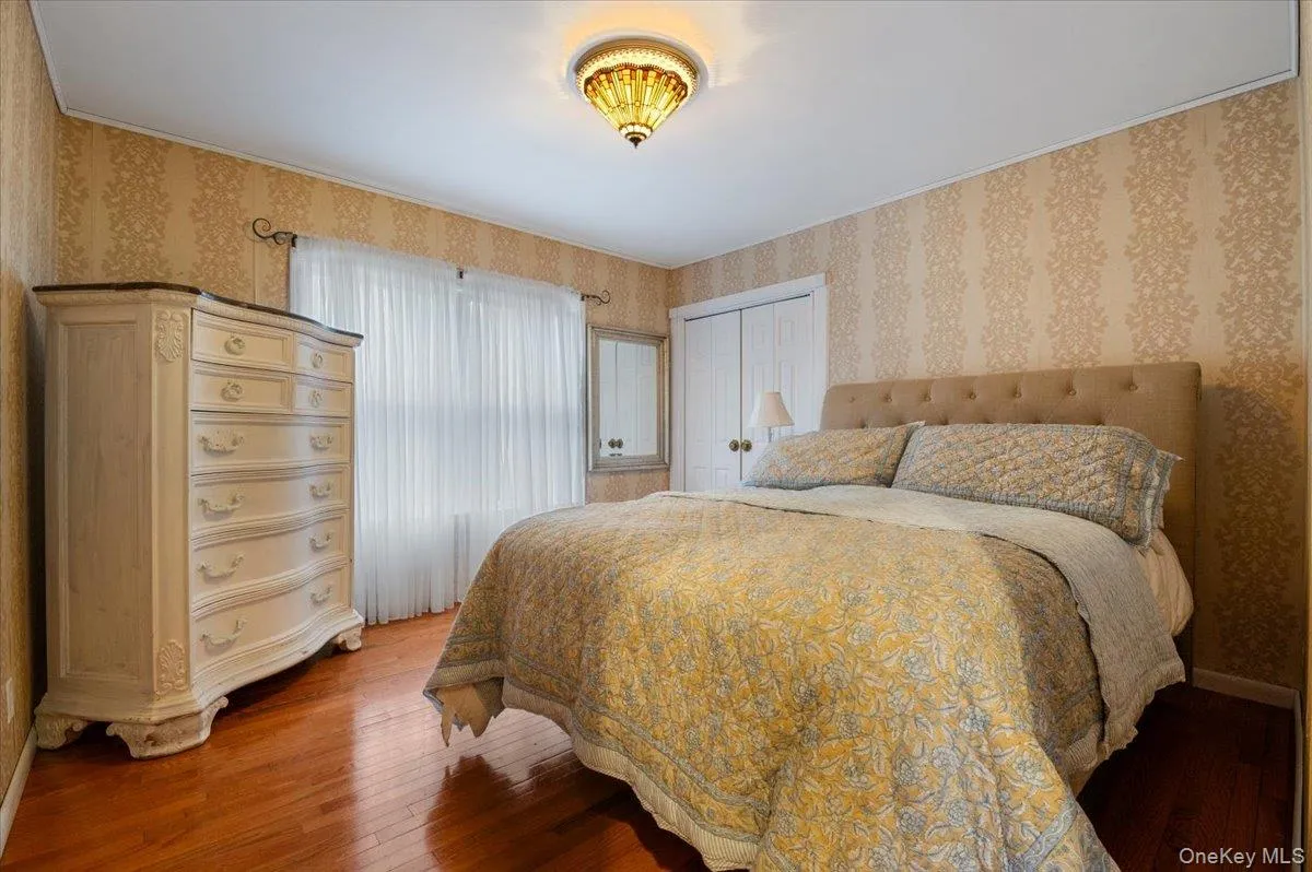 Bedroom with hardwood / wood-style flooring, wallpapered walls, and a closet Bedroom with hardwood / wood-style flooring, wallpapered walls, and a closet