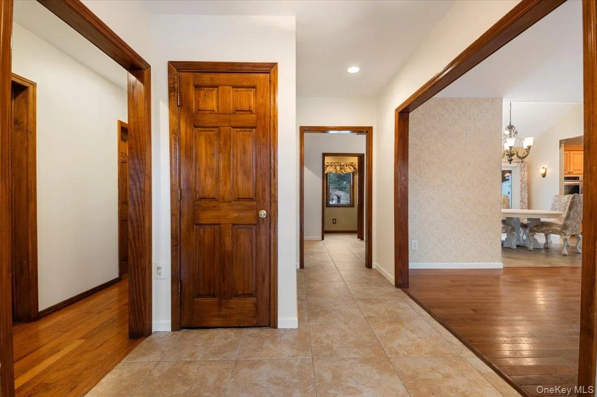 Hallway featuring light wood-style floors, a chandelier, and recessed lighting Hallway featuring light wood-style floors, a chandelier, and recessed lighting