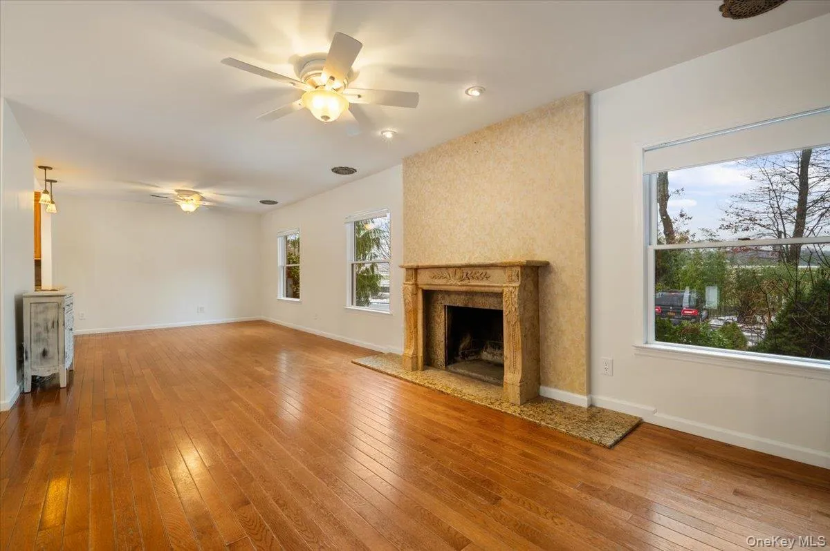 Unfurnished living room with ceiling fan, a premium fireplace, and light wood-style floors Unfurnished living room with ceiling fan, a premium fireplace, and light wood-style floors